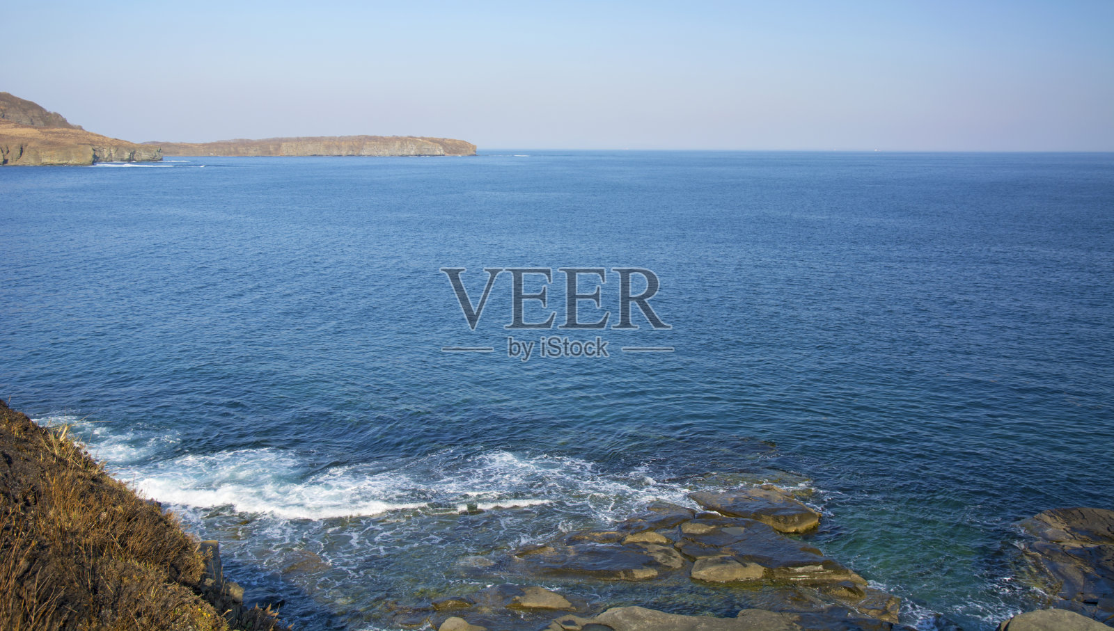 巨大的岩石，在蓝色的海洋中崩塌，与耀眼的阳光，宏伟的岩石照片摄影图片