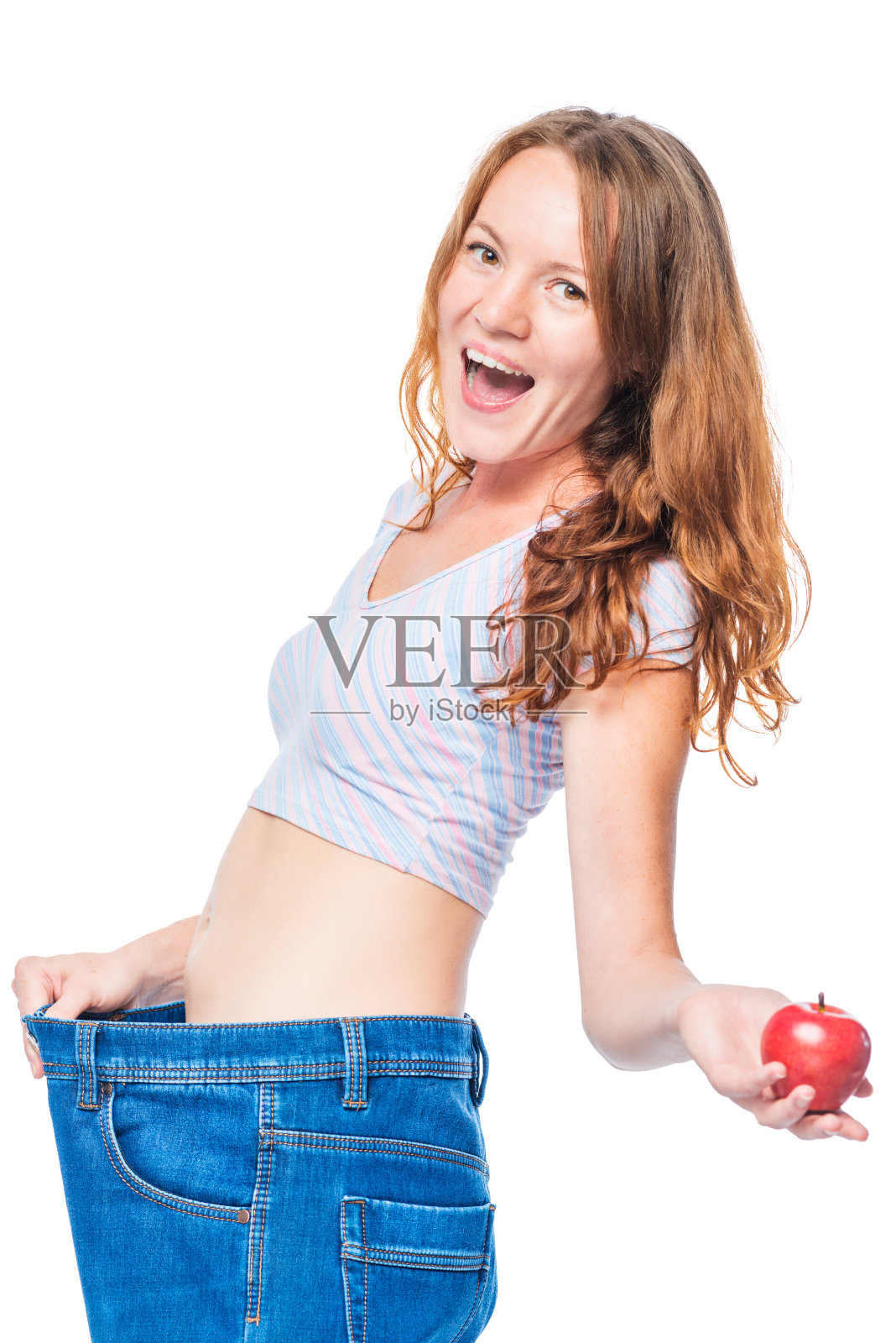 情绪快乐的女孩后苹果饮食支持裤子上的白色背景照片摄影图片