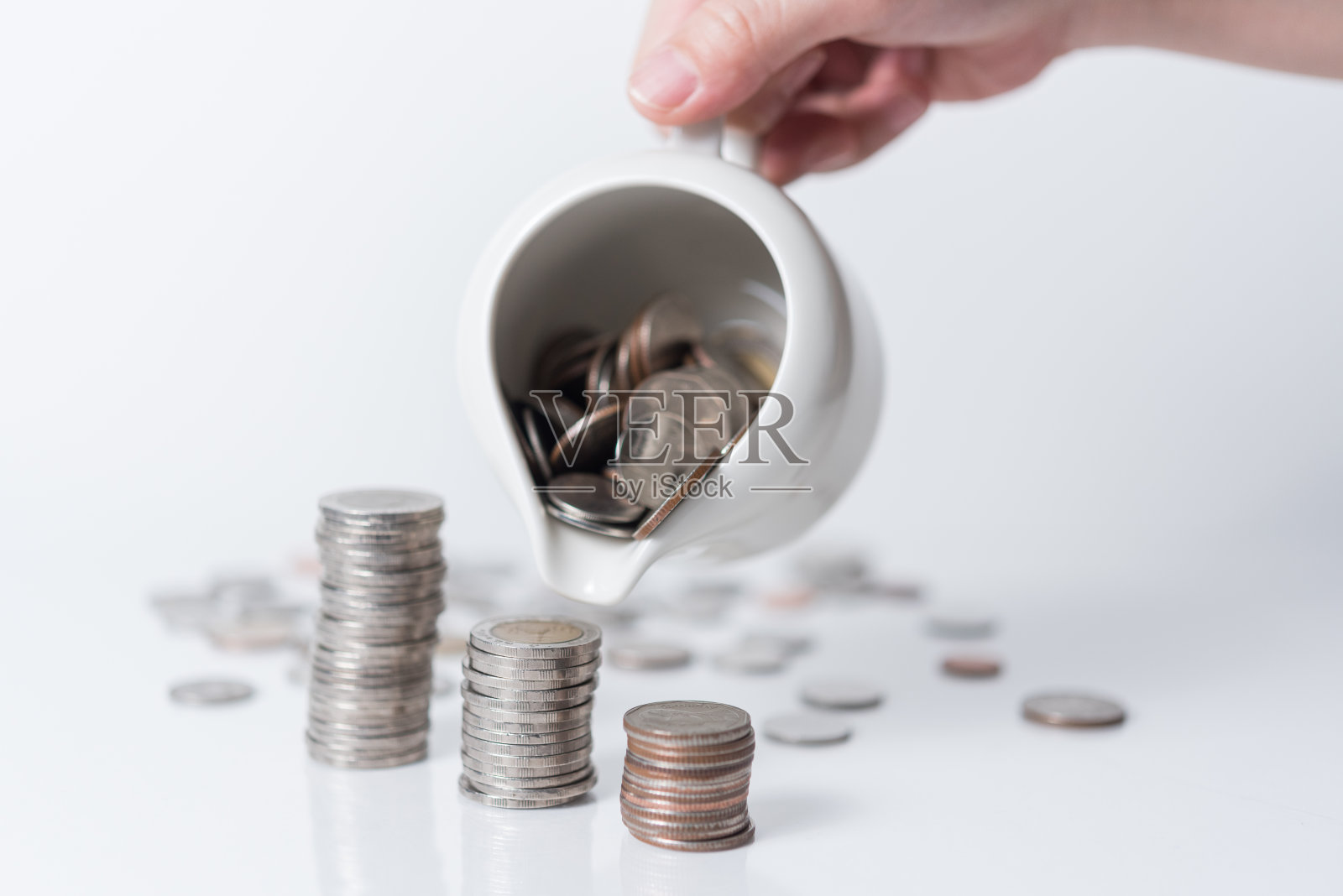 手把硬币放在白色的背景上，省钱照片摄影图片