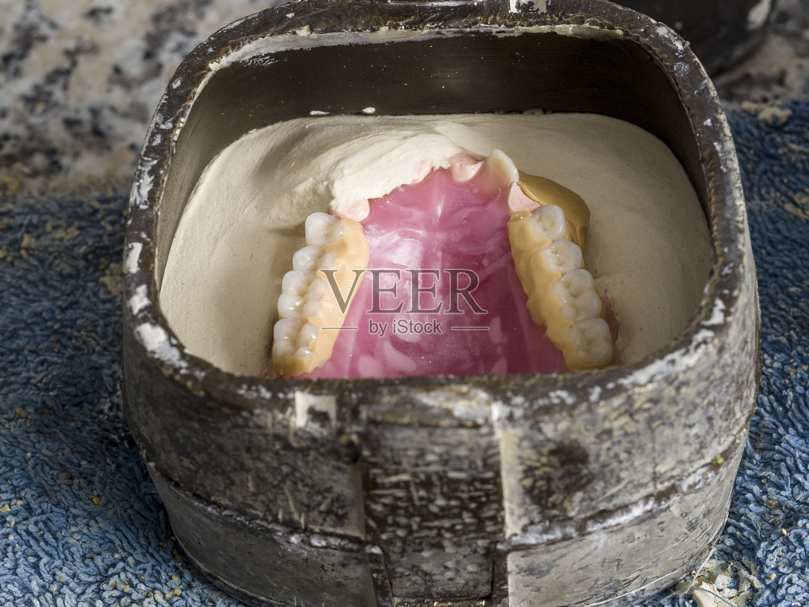 牙科技术人员正在使用一个完整的上部铸型的牙科烧瓶照片摄影图片