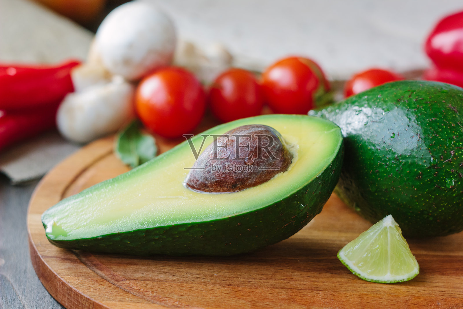 半块鳄梨放在木板上，配上酸橙和番茄。照片摄影图片