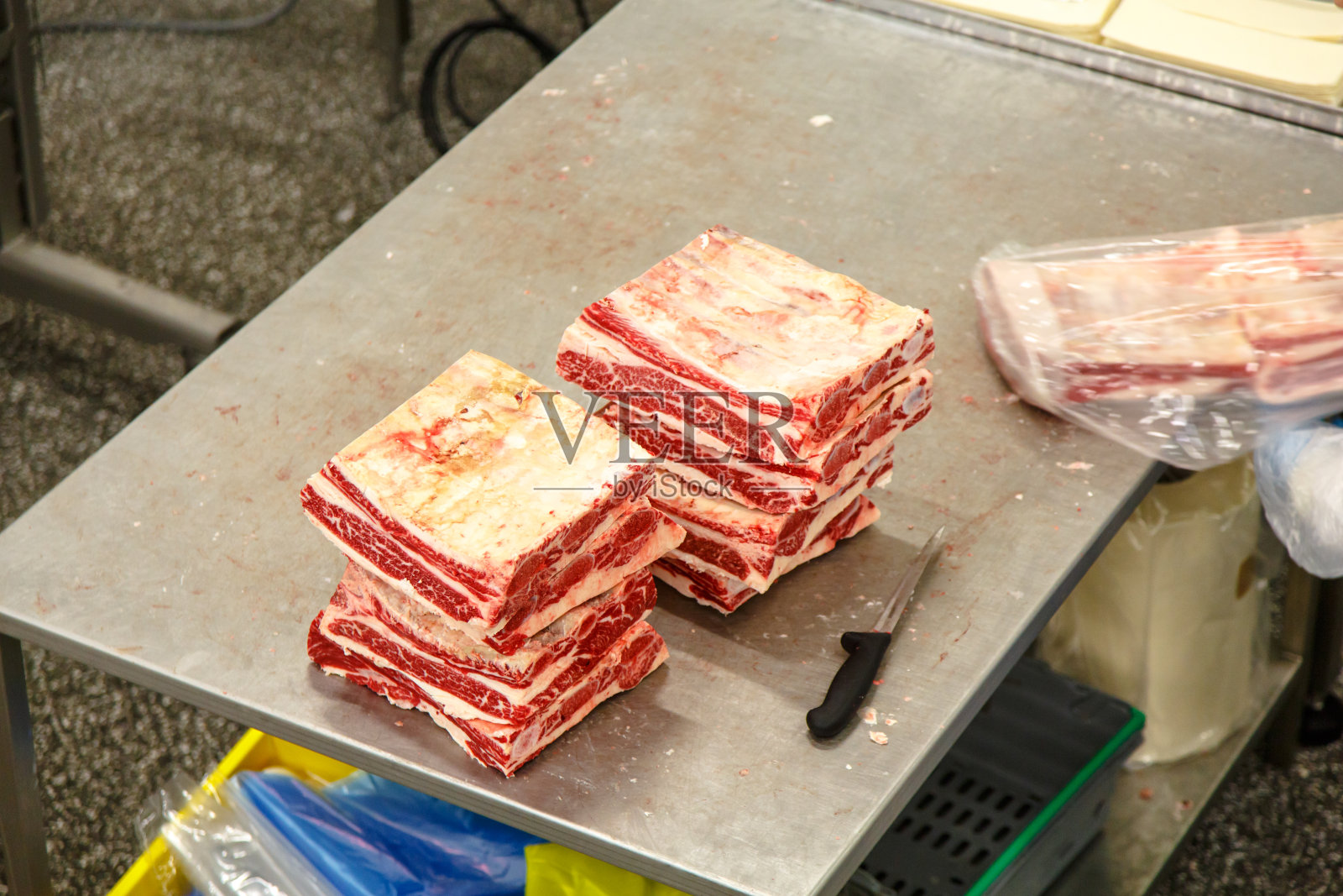 肉类加工厂。大理石花纹牛肉。金属桌子上放着几片培根。照片摄影图片