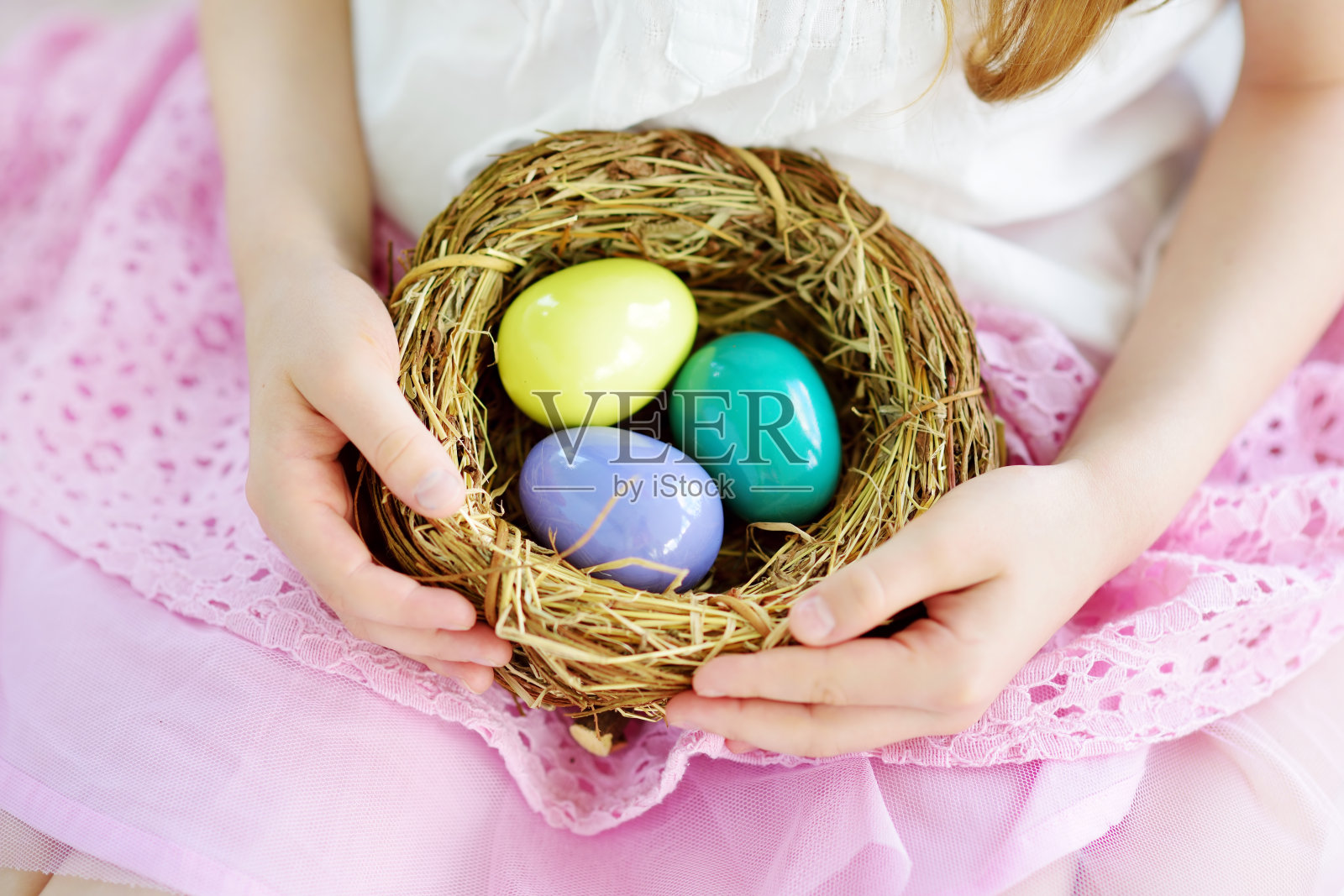复活节那天，可爱的小女孩在家里抱着一窝五颜六色的复活节彩蛋照片摄影图片