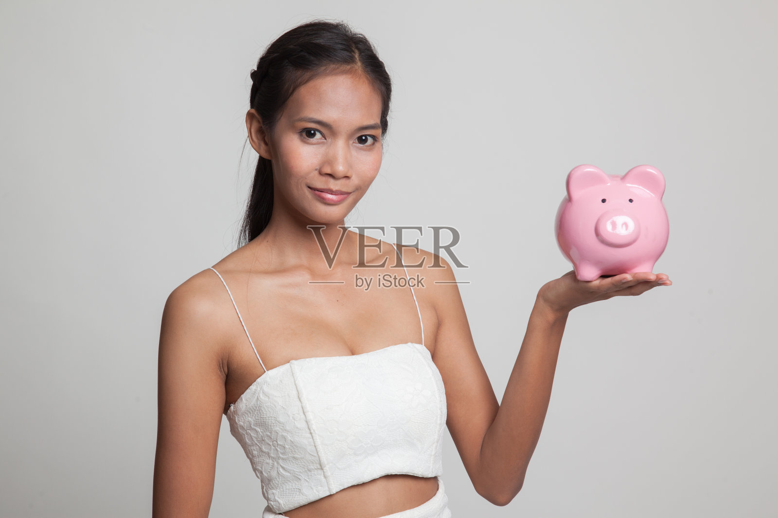 拿着猪硬币的年轻亚洲女人。照片摄影图片