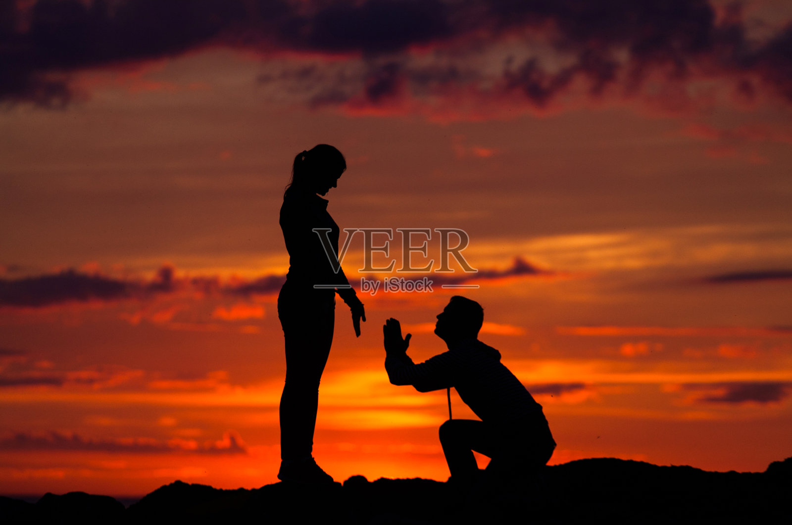 女人和男人的剪影在一个阴天的海滩上的彩色日落背景照片摄影图片