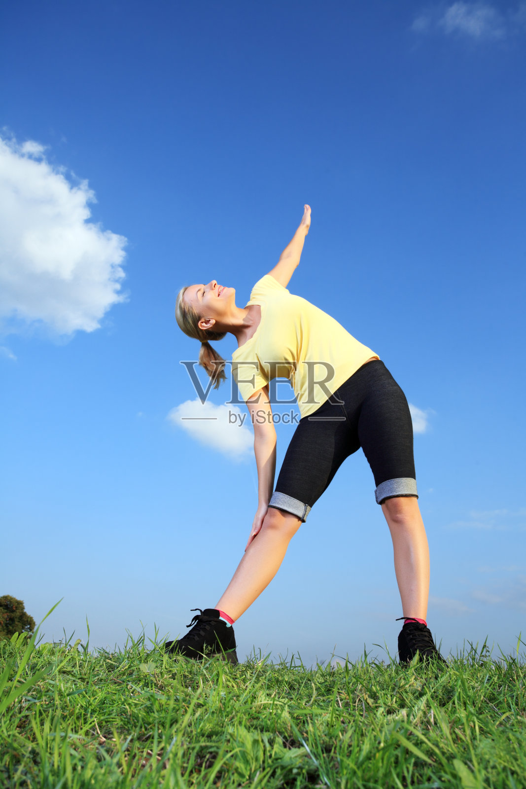 在草地上锻炼的女人。照片摄影图片