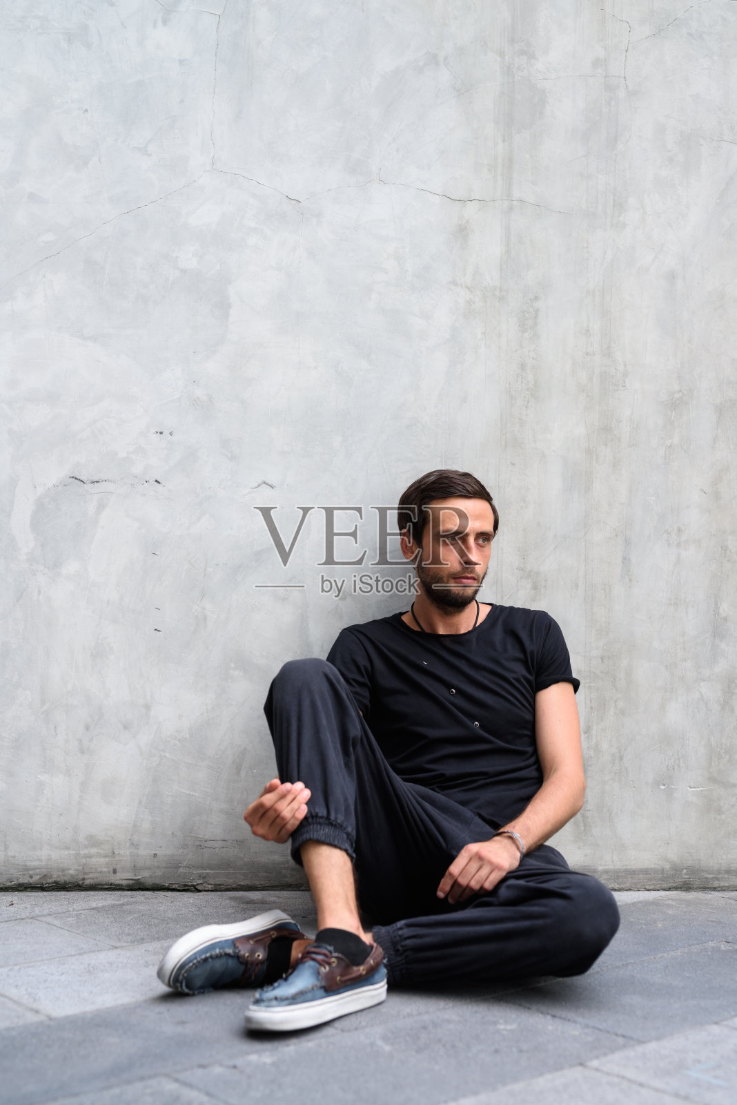 一个英俊男子的肖像靠在外面街道上的旧混凝土墙上照片摄影图片