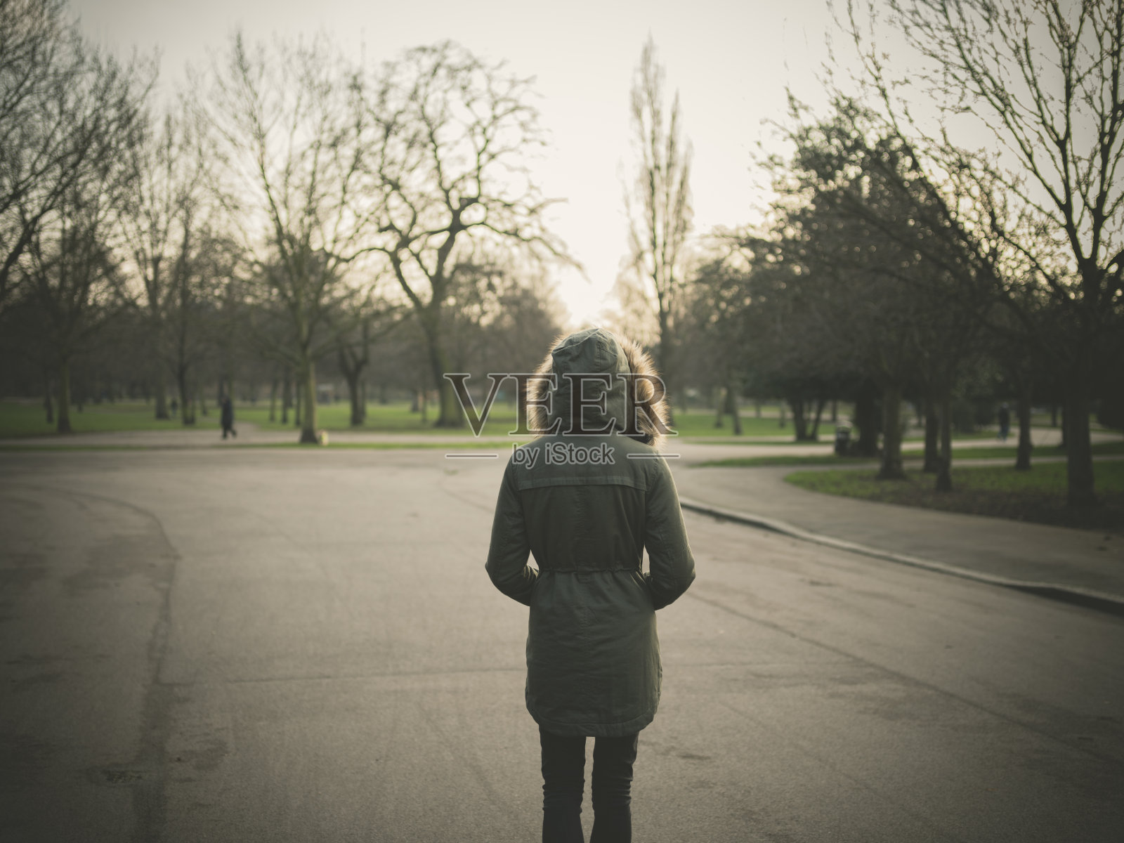 夕阳西下时，穿着暖和外套的人站在公园里照片摄影图片