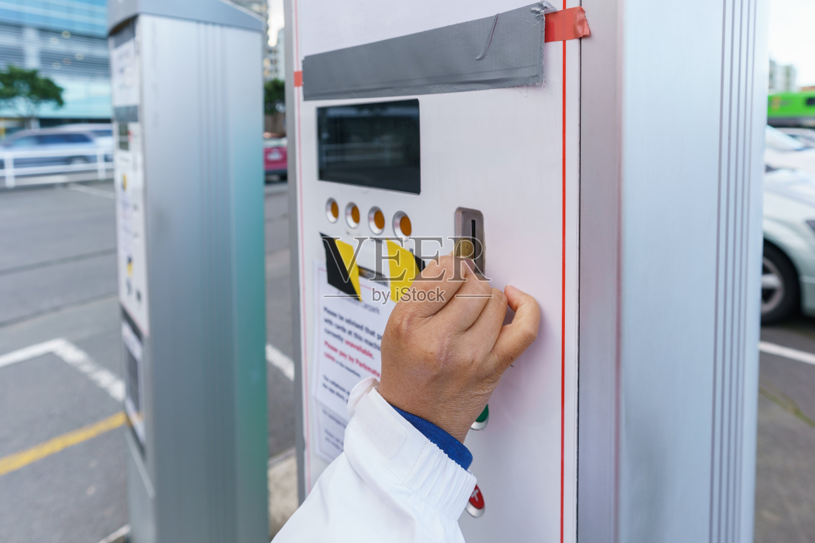 一名女子将硬币插入汽车自动售货机，为市内停车场付款照片摄影图片