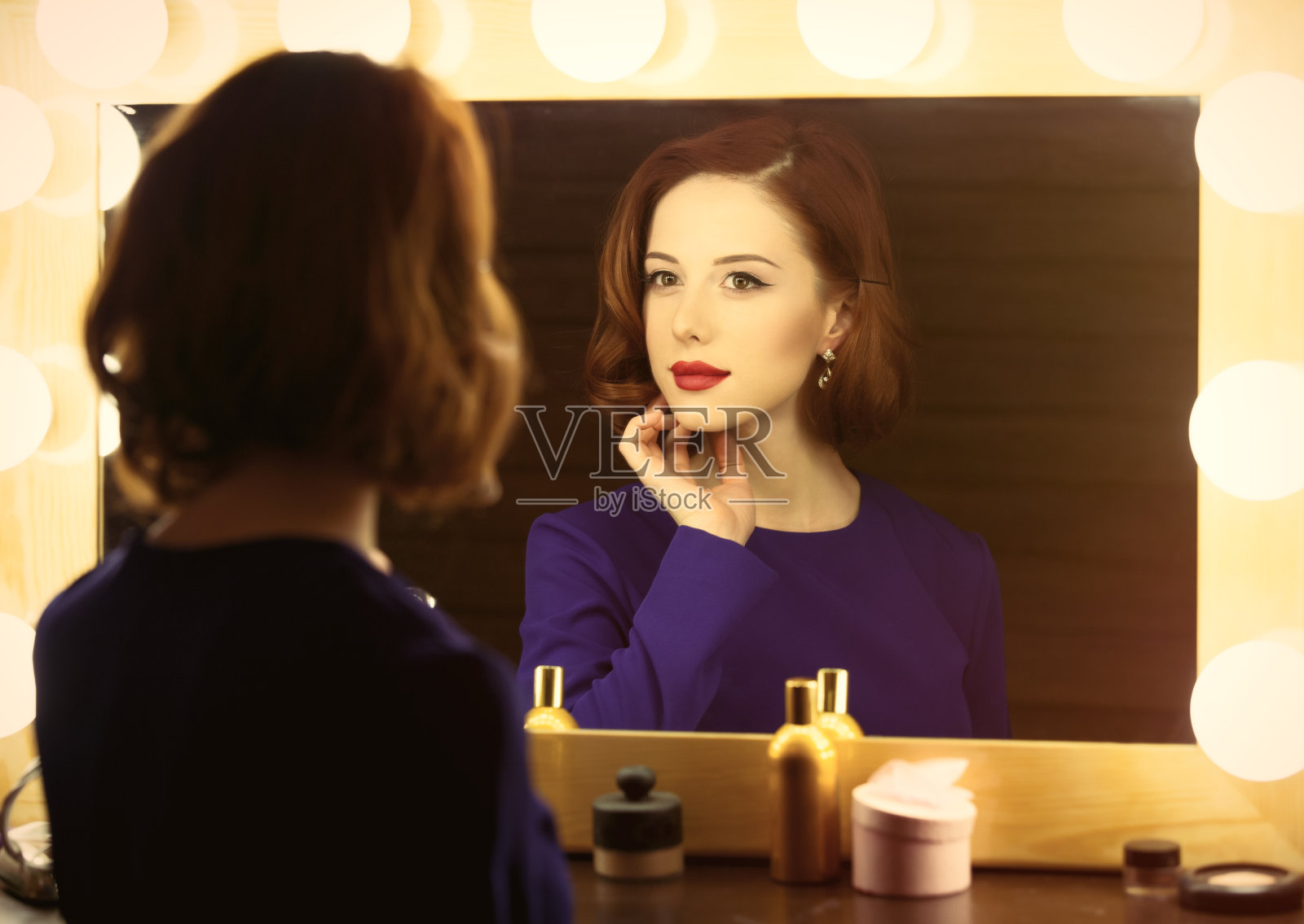 一张漂亮的年轻女子在灯光下看着自己的照片照片摄影图片