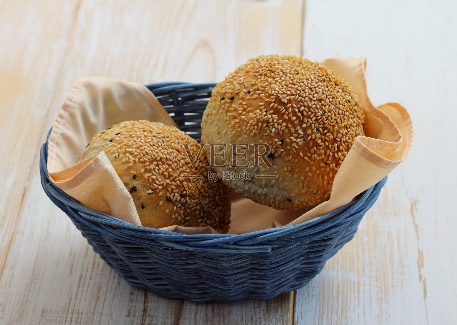 篮子蓝色的芝麻面包圈。照片摄影图片