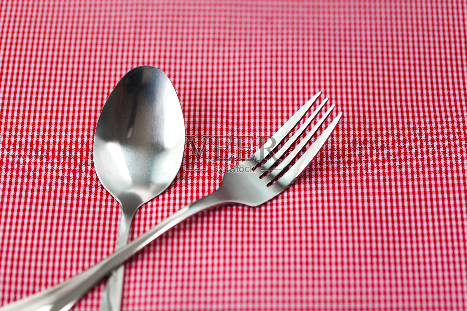 红色布料上的银叉和银匙。有选择性的重点。照片摄影图片