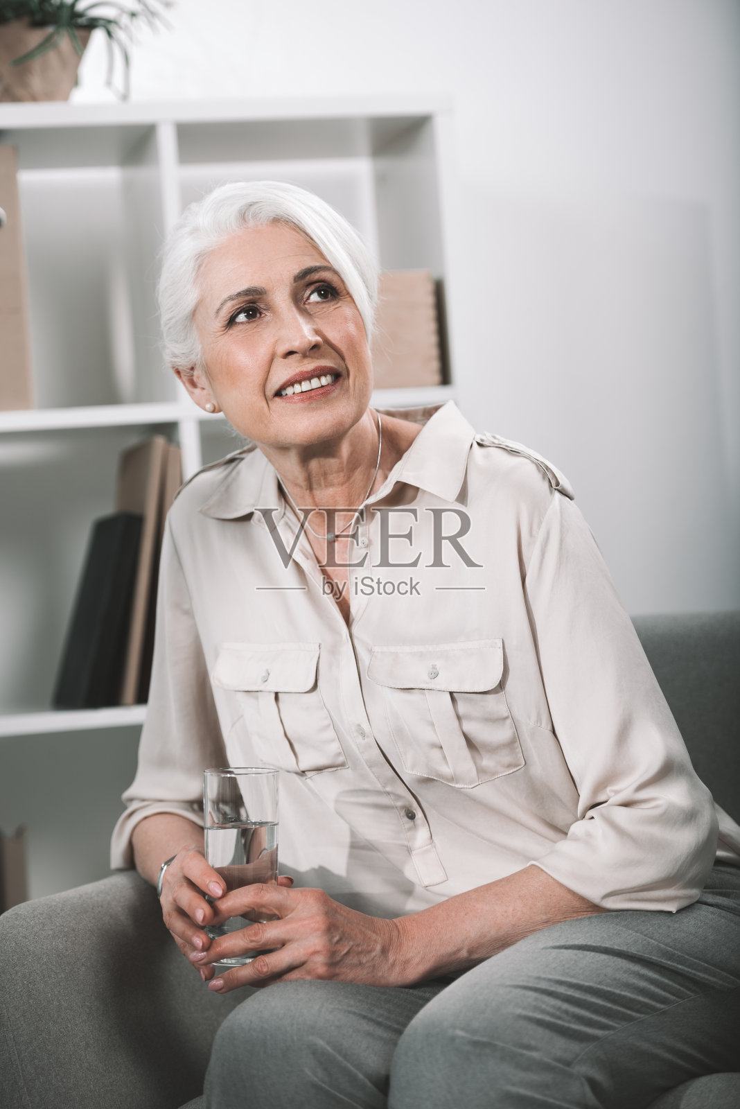 一位深思熟虑的资深女商人在办公室拿着一杯水的肖像照片摄影图片