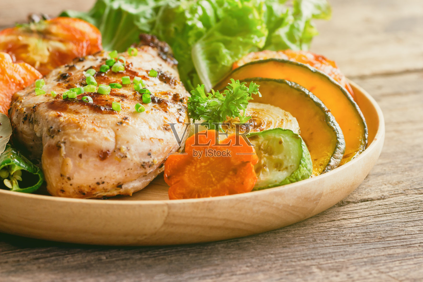 自制鸡胸肉烧烤，配上烤蔬菜。午餐或晚餐美味的烤鸡和烤蔬菜。质朴的木桌上放着烤鸡胸肉。照片摄影图片