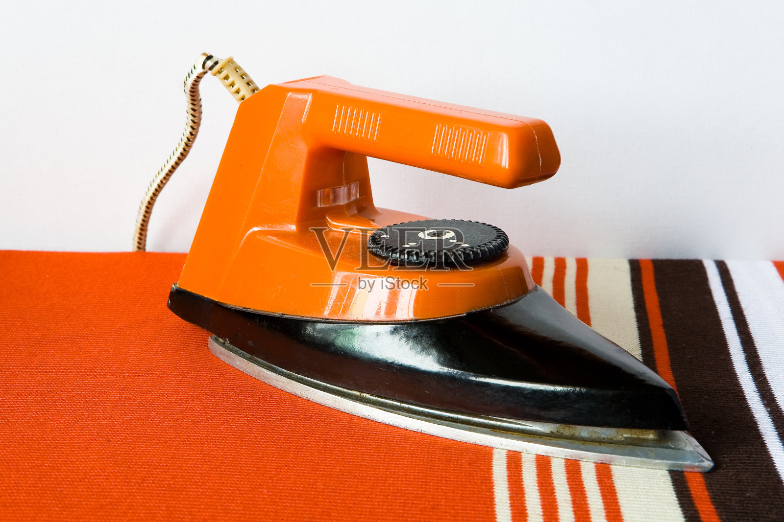 带条纹绳的旧赤陶土熨斗站在条纹织物上。照片摄影图片