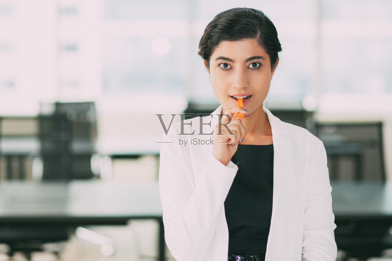 自信的亚洲年轻女商人吃胡萝卜照片摄影图片