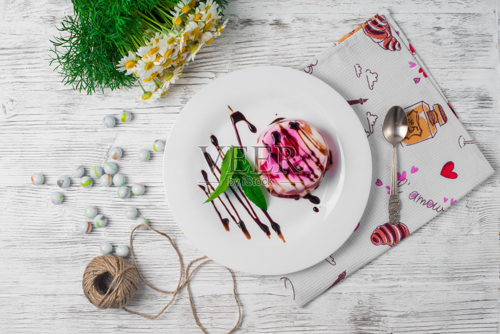 旧木桌上黄色的针织餐巾上放着一个盘子和勺子，上面放着水果果冻和杏子。有选择性的重点照片摄影图片