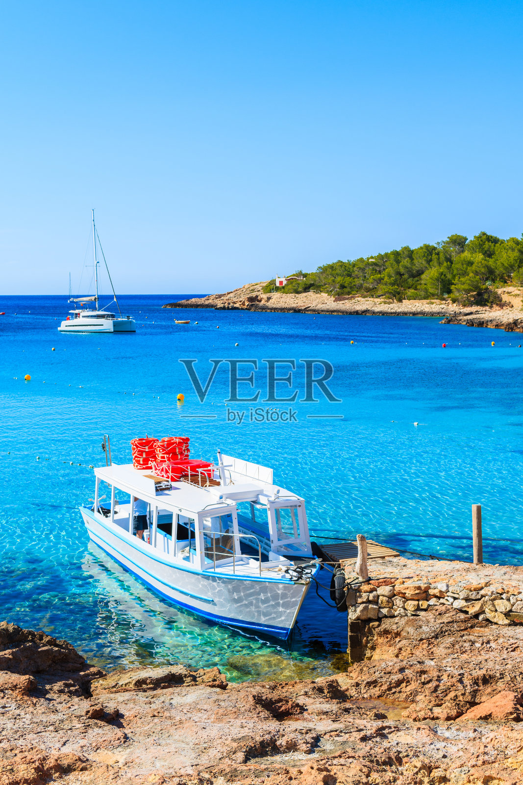 白色和蓝色的渡轮，游客停泊在卡拉波提纳克斯湾，伊比沙岛，西班牙照片摄影图片