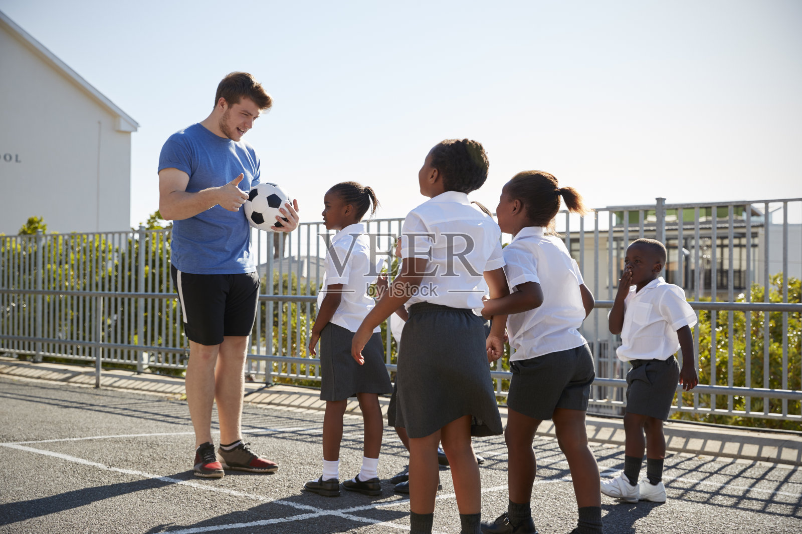 孩子们在学校操场上，老师拿着球照片摄影图片