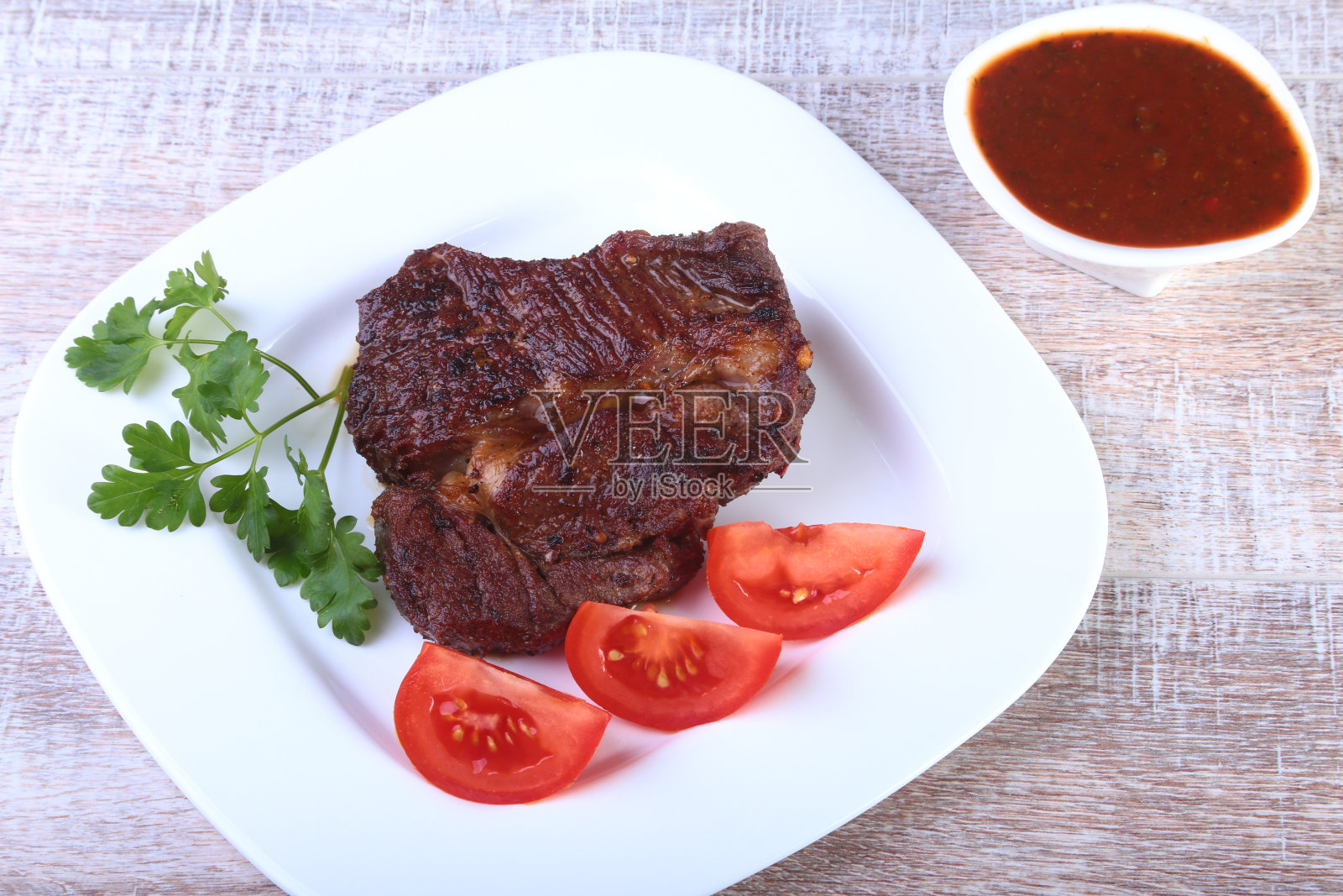 烤牛扒配番茄、亚洲红辣椒、蒜蓉酱，放在木底盘上。照片摄影图片