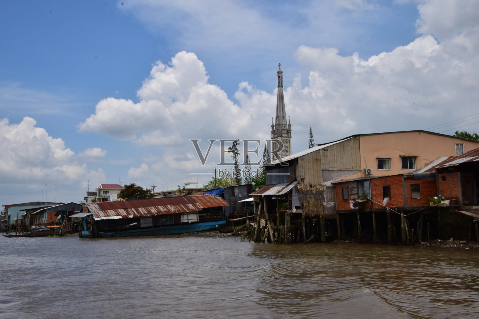 在湄公河三角洲破败的棚屋和建筑之上高耸的教堂尖顶照片摄影图片