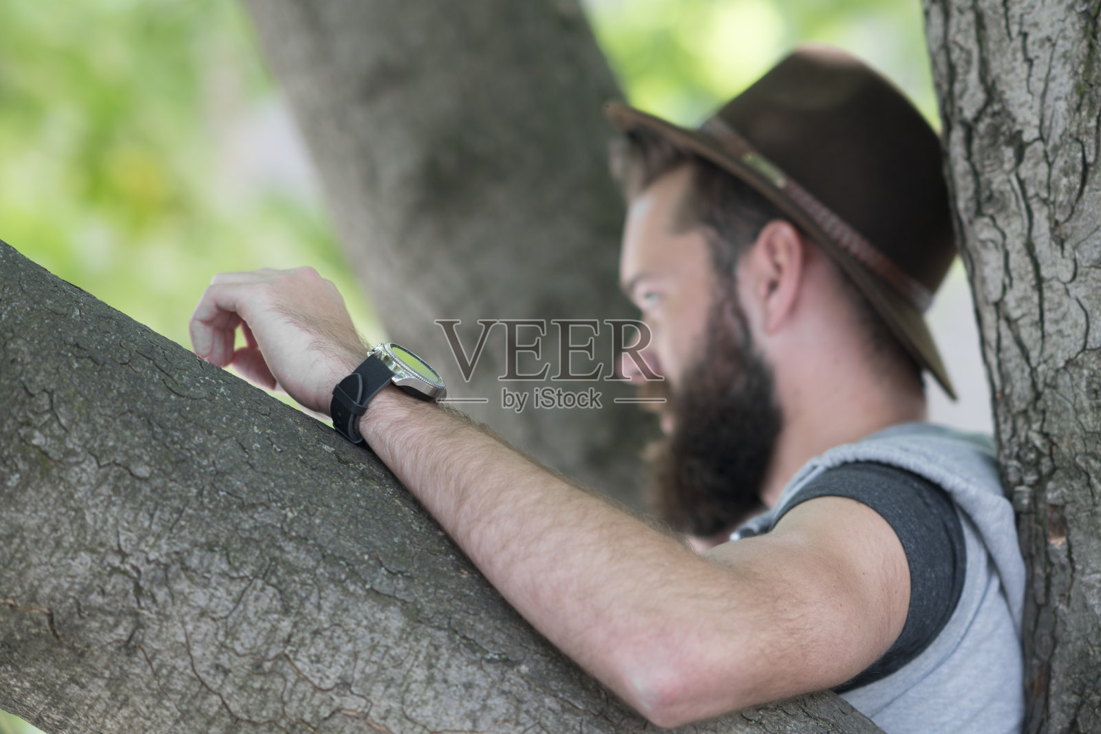 一个靠在树上的嬉皮士。选择性地聚焦在他的胳膊上照片摄影图片