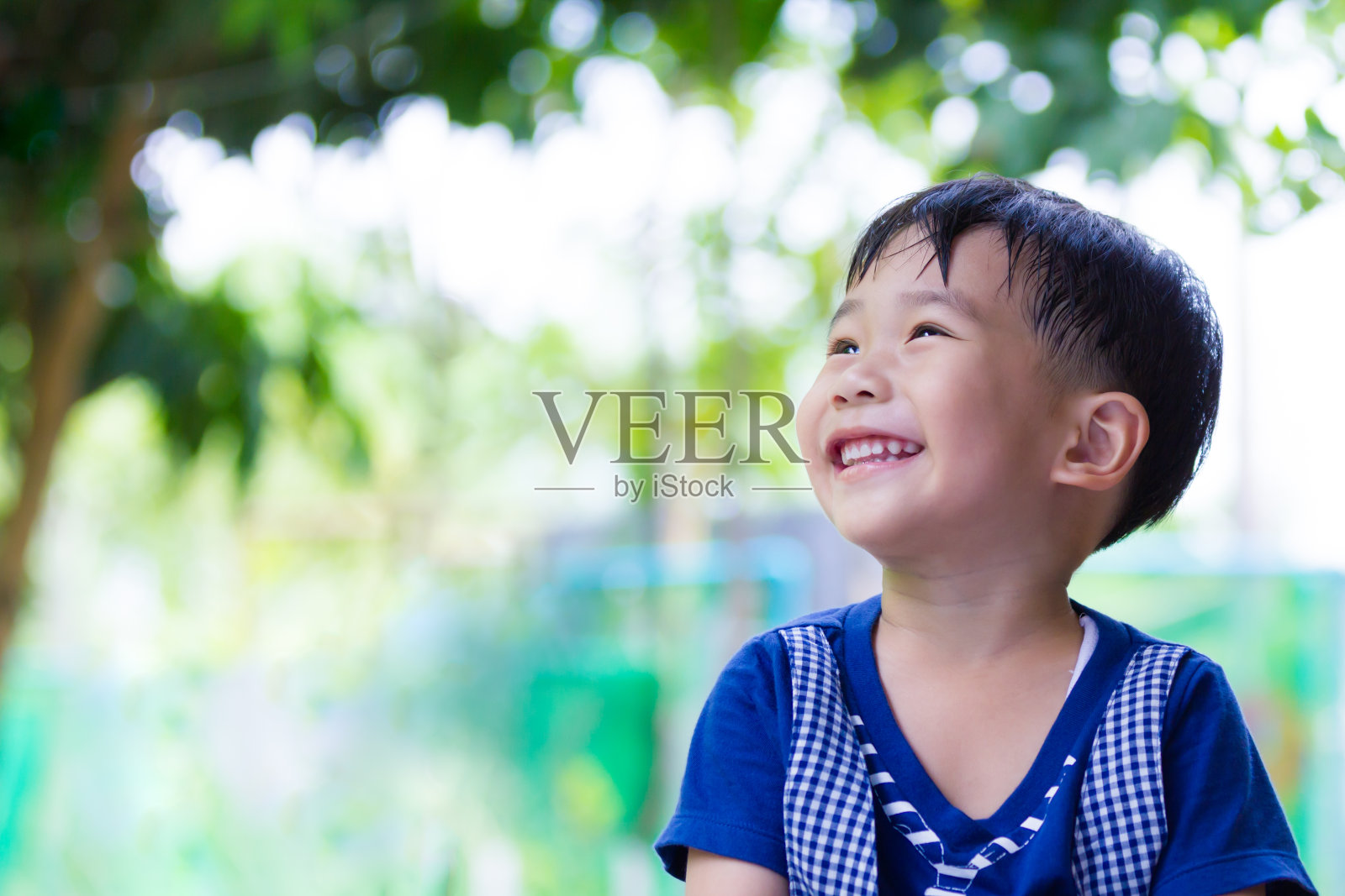 快乐的亚洲男孩抬头看公园。白天出门，度假旅游。照片摄影图片