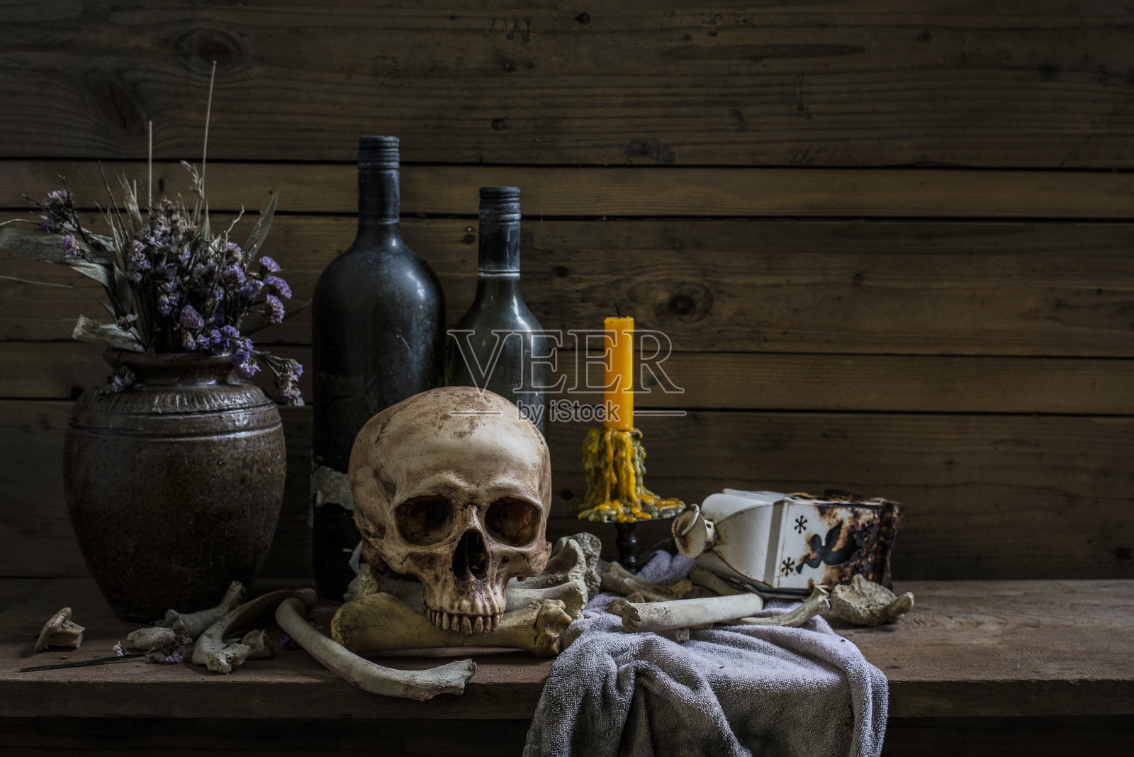 人的头骨和堆骨与蜡烛光，静物生活方式在木桌照片摄影图片