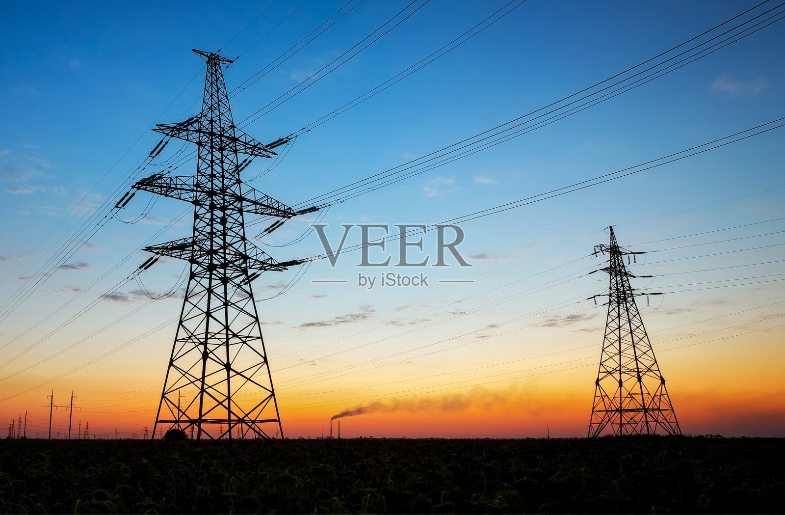 日落时分，电线塔和高压电线在田野上的剪影。在日出时布线电能照片摄影图片
