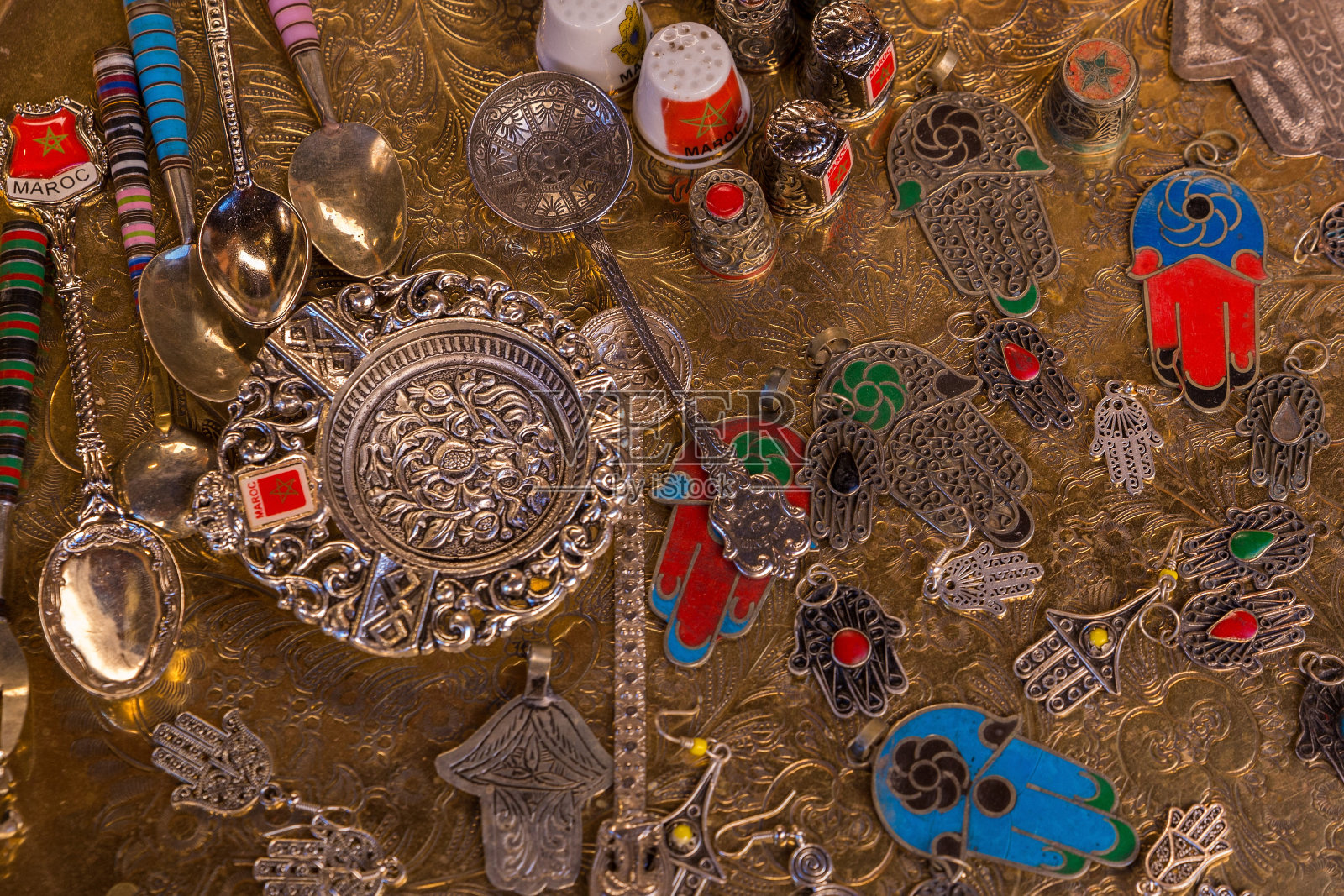 黄铜托盘上放着纪念品勺子、护身符、顶针和烟灰缸。照片摄影图片