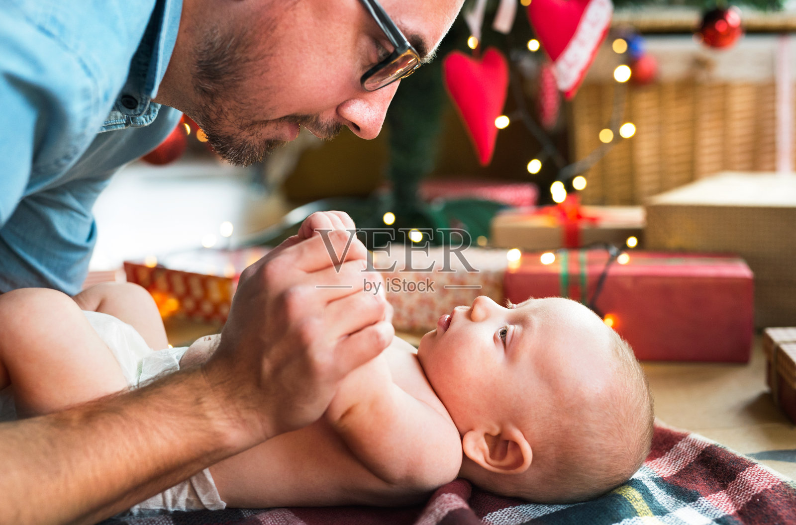 父亲抱着男婴在圣诞树前照片摄影图片
