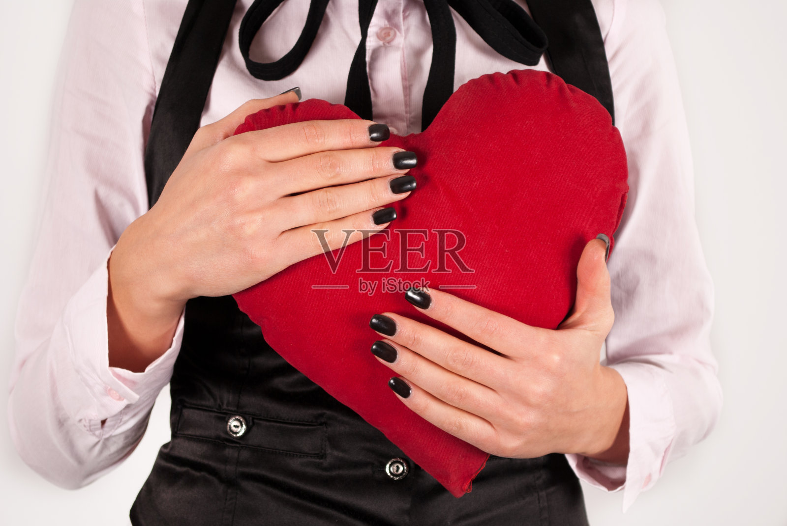 女子在优雅的衣服和领带拥抱大红心枕头照片摄影图片