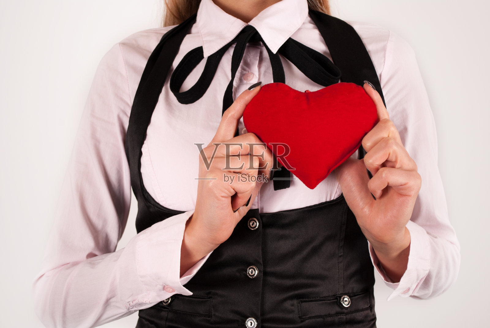 在白色的背景上，拿着领结的女人手里拿着红色的心照片摄影图片