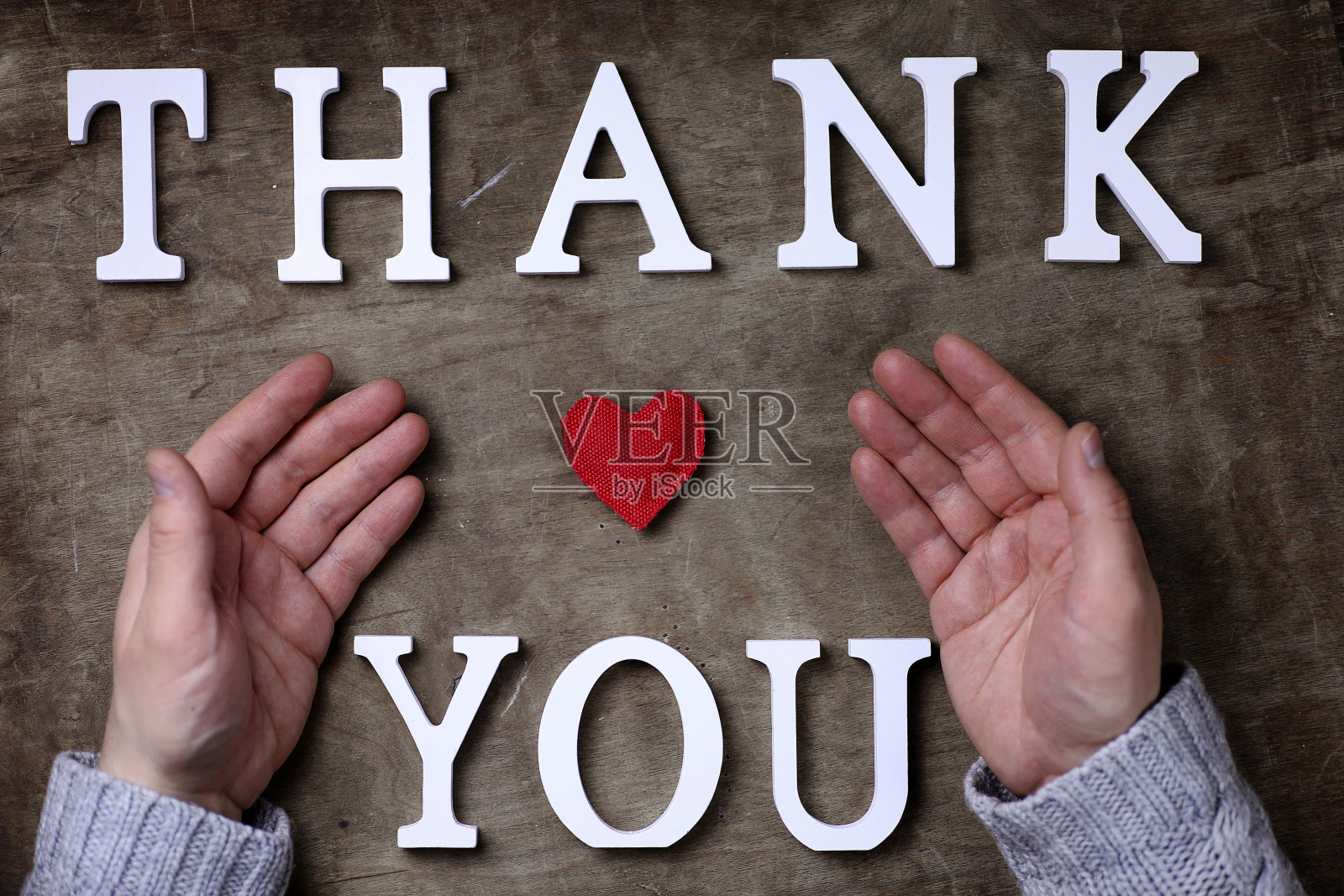 白色木制字母拼出的感谢语在桌上和手上照片摄影图片