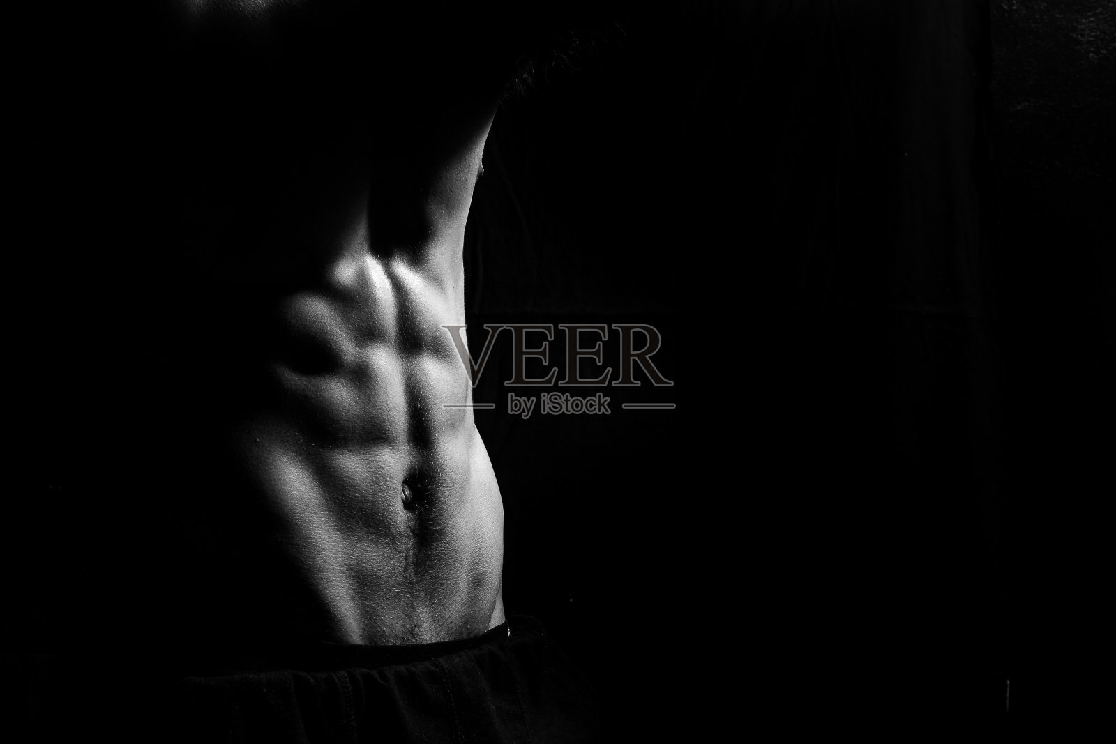男性健身模型显示肌肉在工作室与黑色背景照片摄影图片