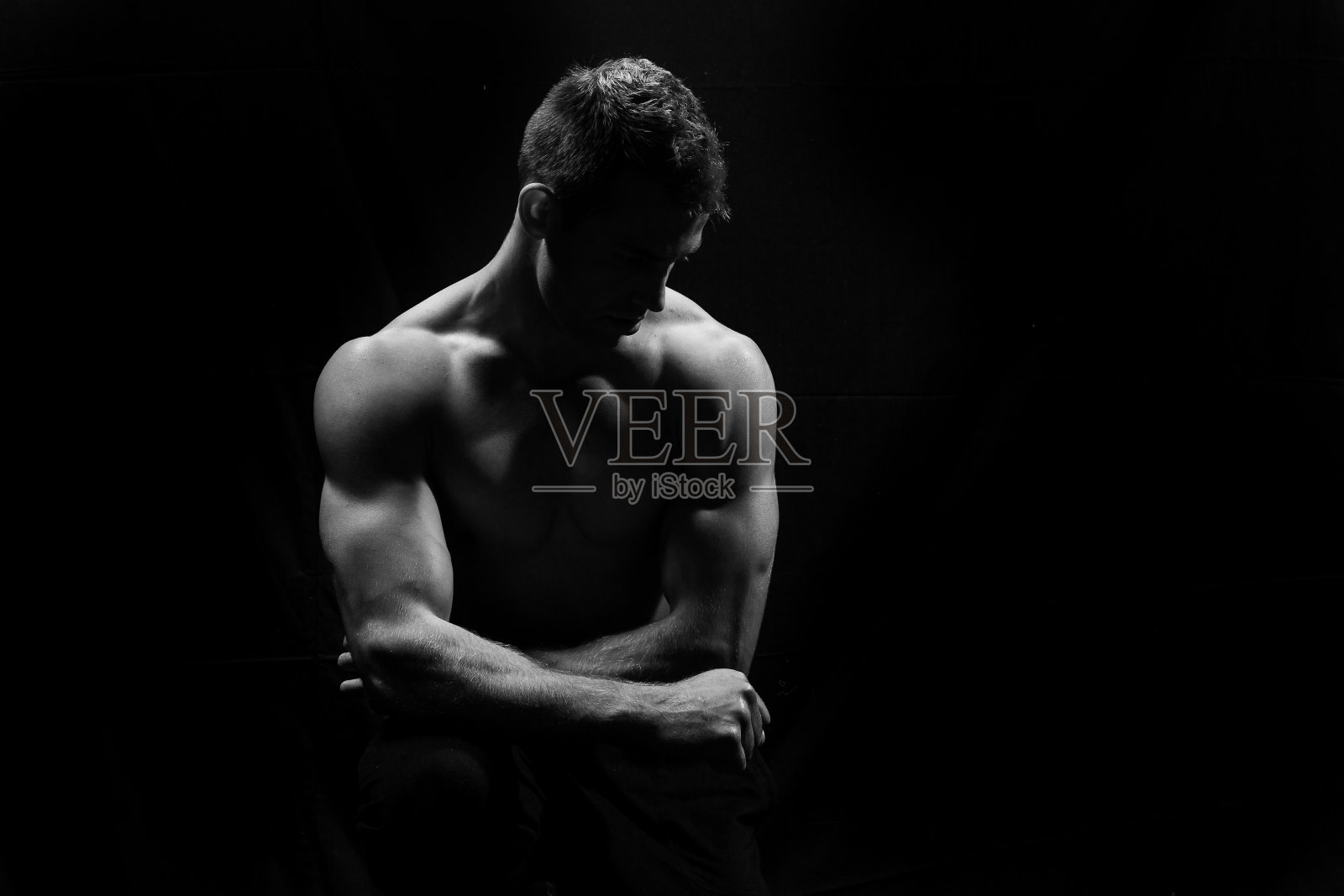 男性健身模型显示肌肉在工作室与黑色背景照片摄影图片