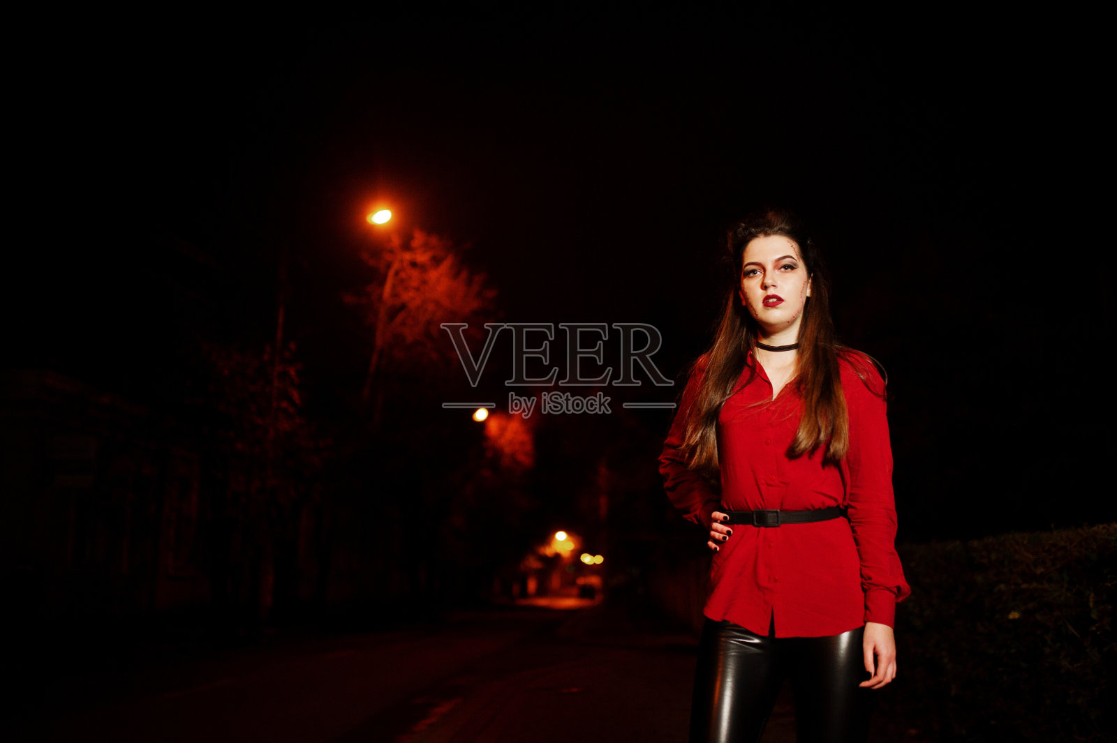 黑色女孩穿着红色的衬衫和明亮的化妆在夜晚的街道户外。万圣节的主题。照片摄影图片