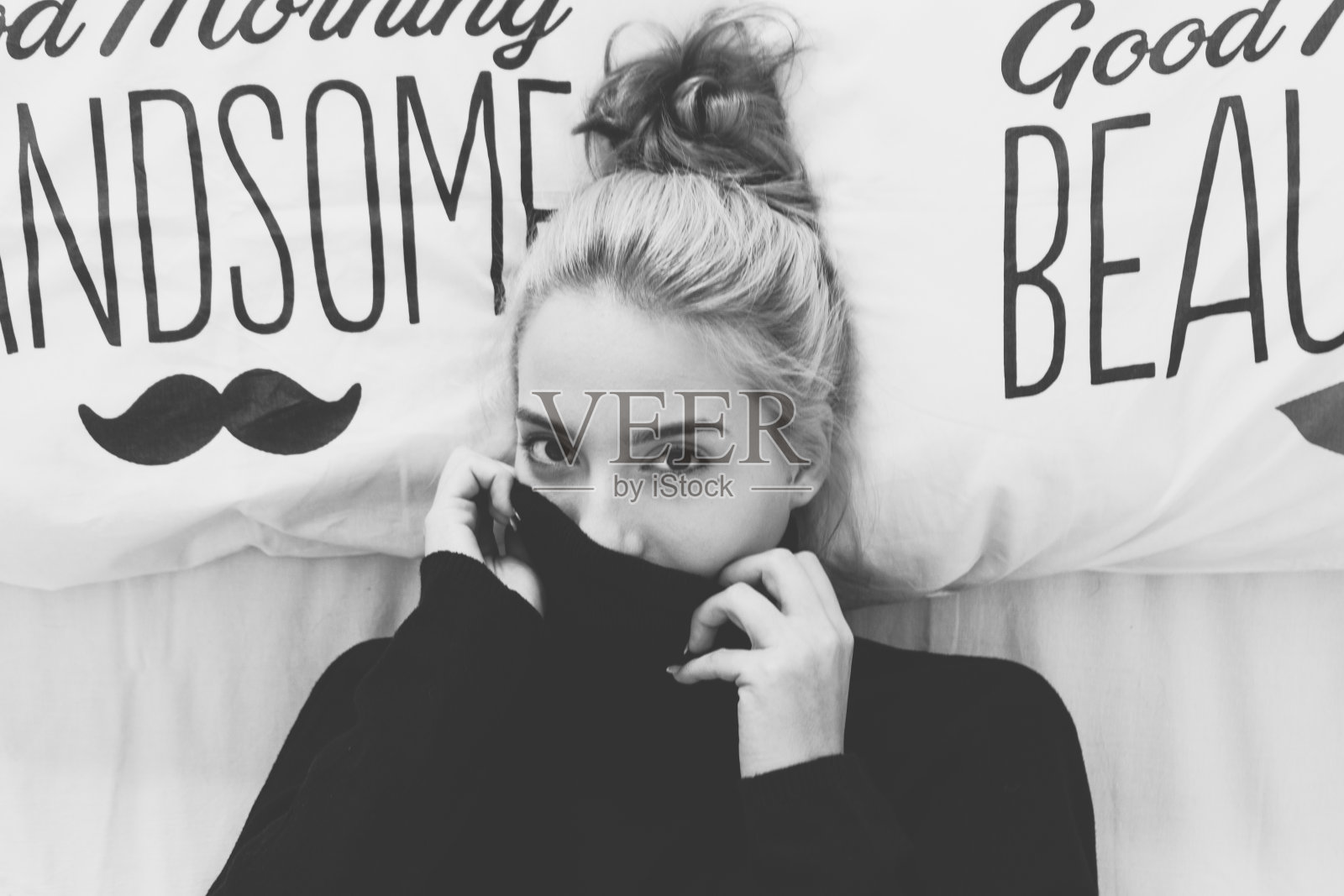 顽皮的女人躺在床上，遮住了她的脸照片摄影图片