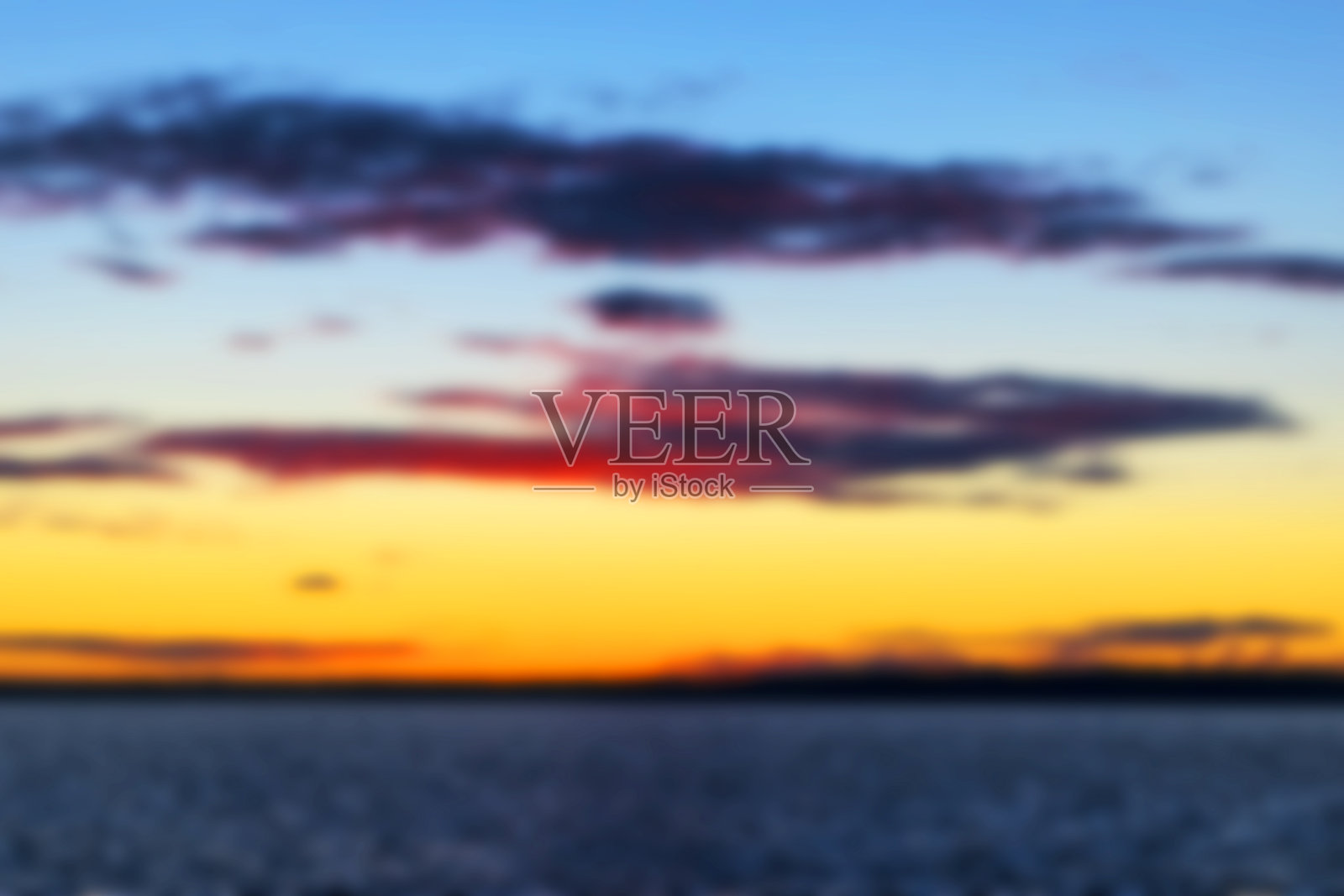 模糊的背景与日落通过云越过海洋，模糊金色的太阳，海和天空。模糊。软lightining照片摄影图片