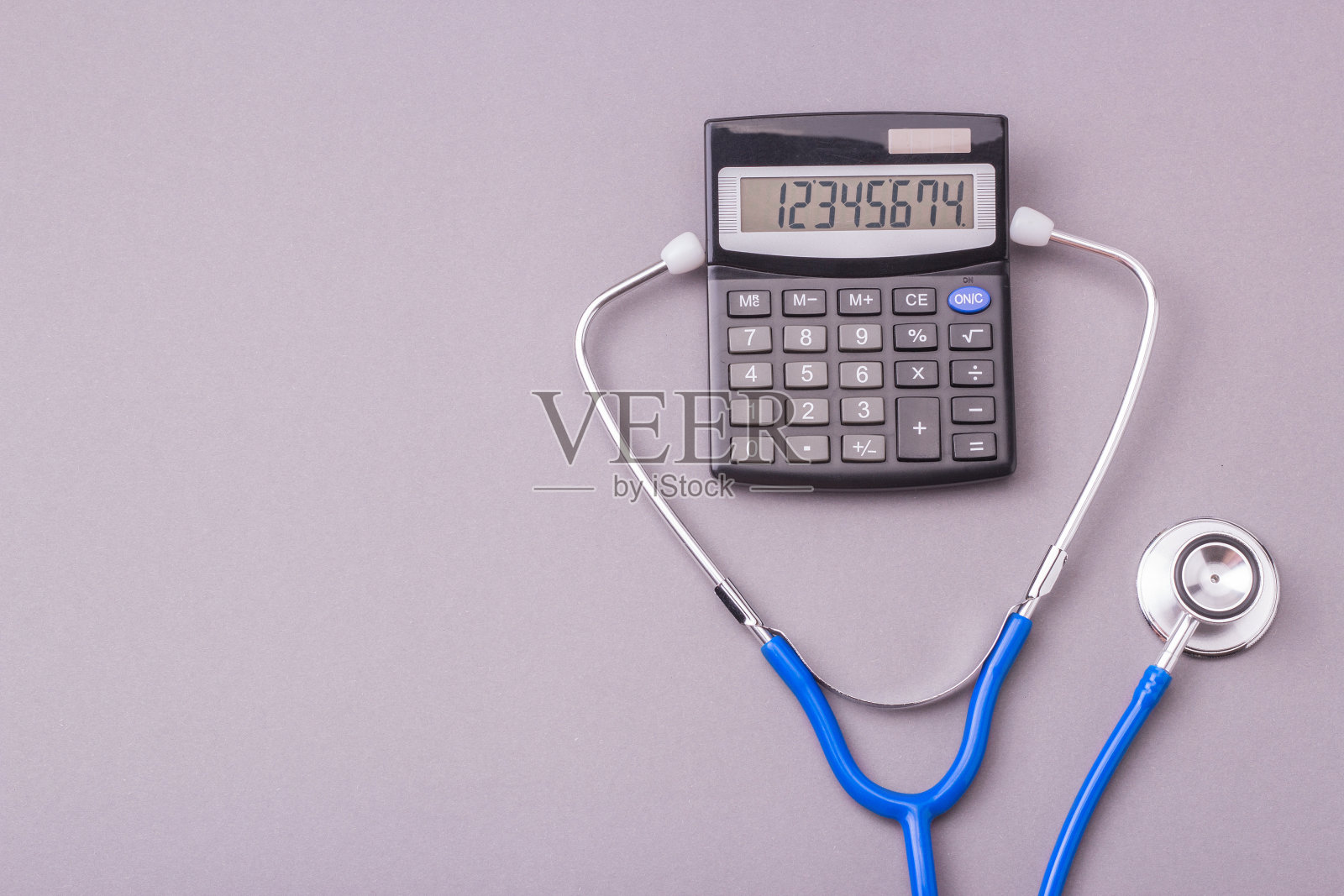听诊器和计算器在灰色背景。亲爱的药品或医疗保险人。文本复制空间照片摄影图片