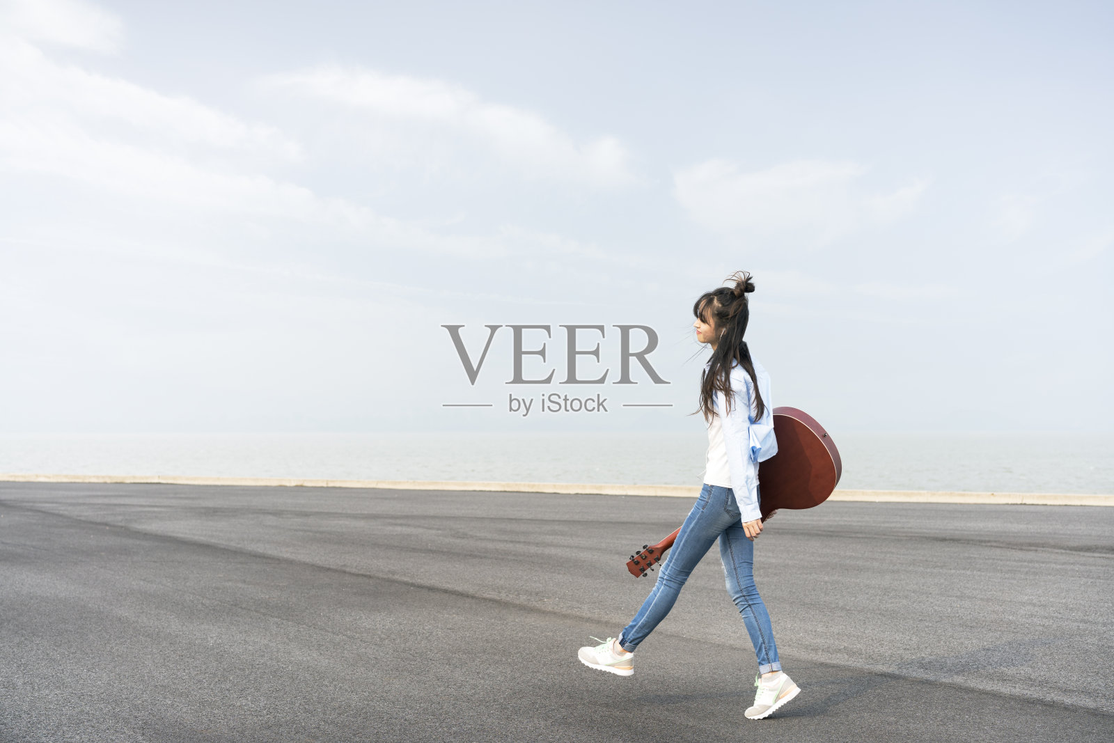 年轻风格的女人拿着吉他在天空中行走照片摄影图片