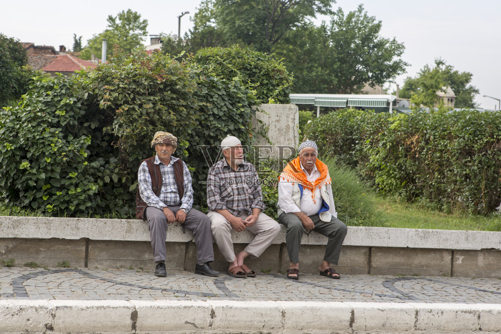 穿着民俗服装的老人坐在土耳其edirne街头的墙边照片摄影图片