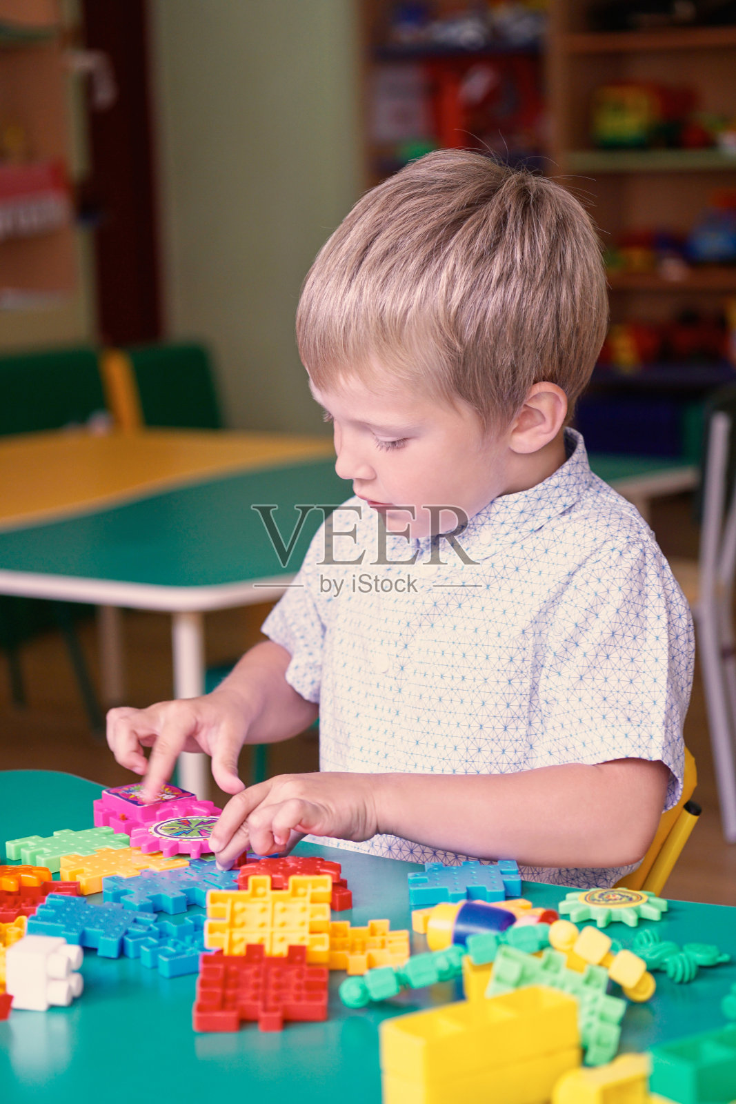一个可爱的小男孩在孩子们房间的桌子上玩耍。照片摄影图片