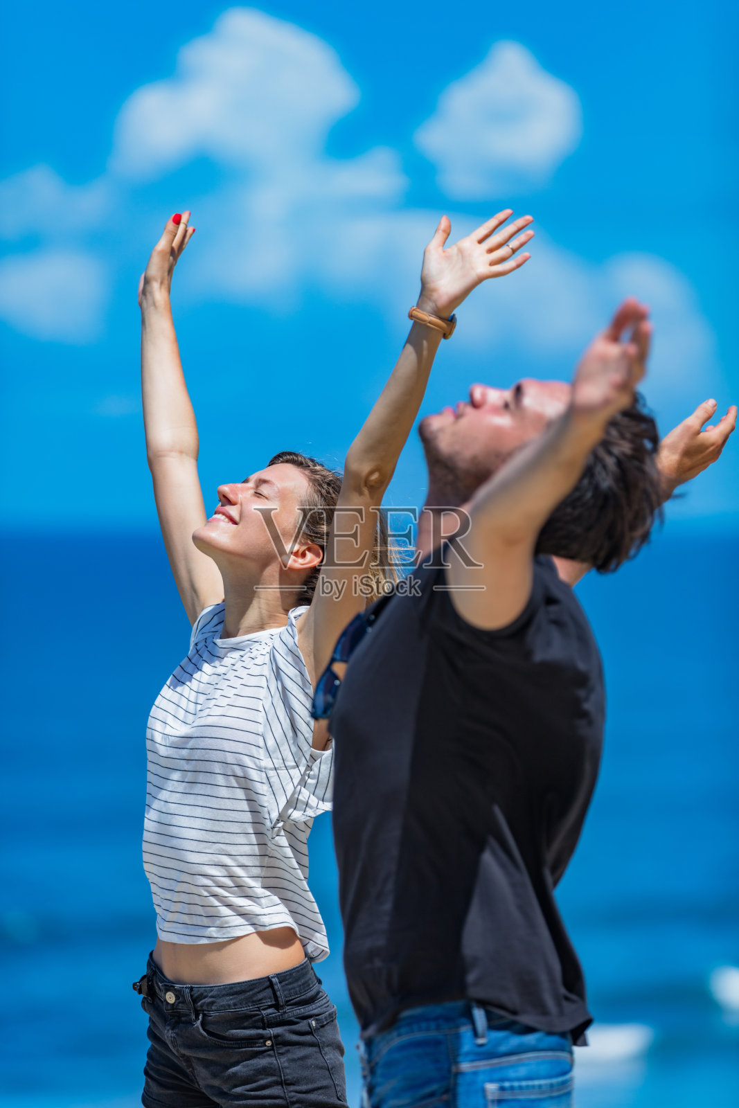 一对夫妇在海边张开双臂享受。照片摄影图片