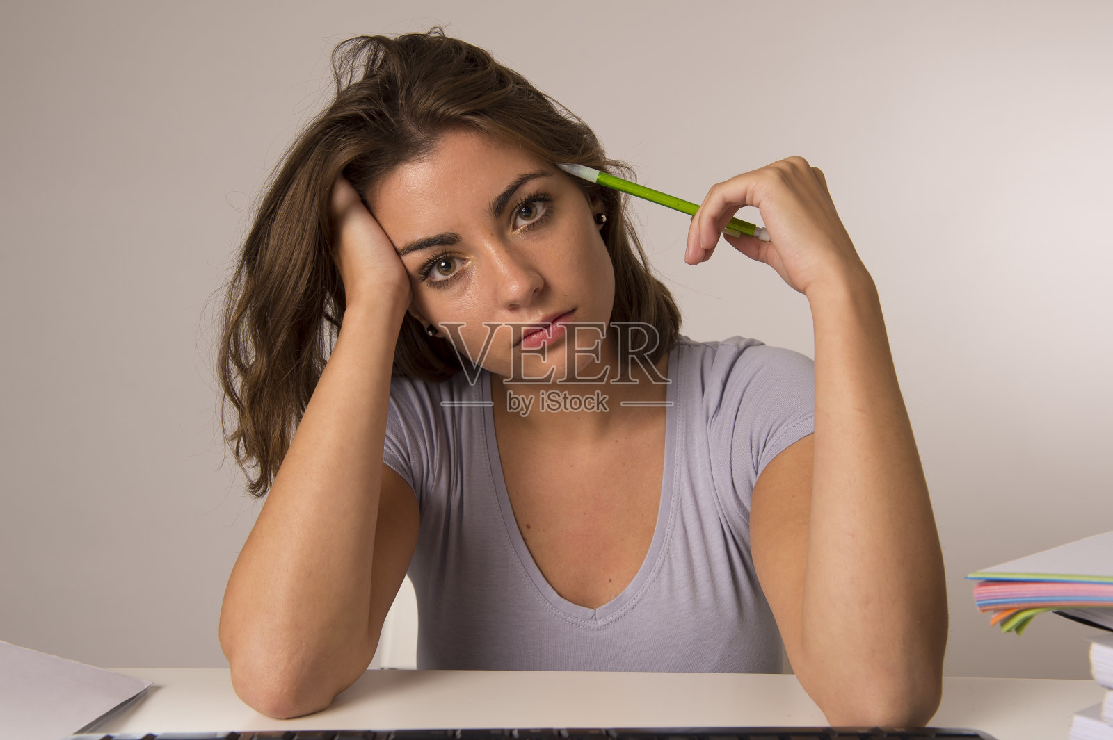 年轻迷人的女学生或女职员坐在电脑桌前，看起来疲惫、疲惫和无聊照片摄影图片