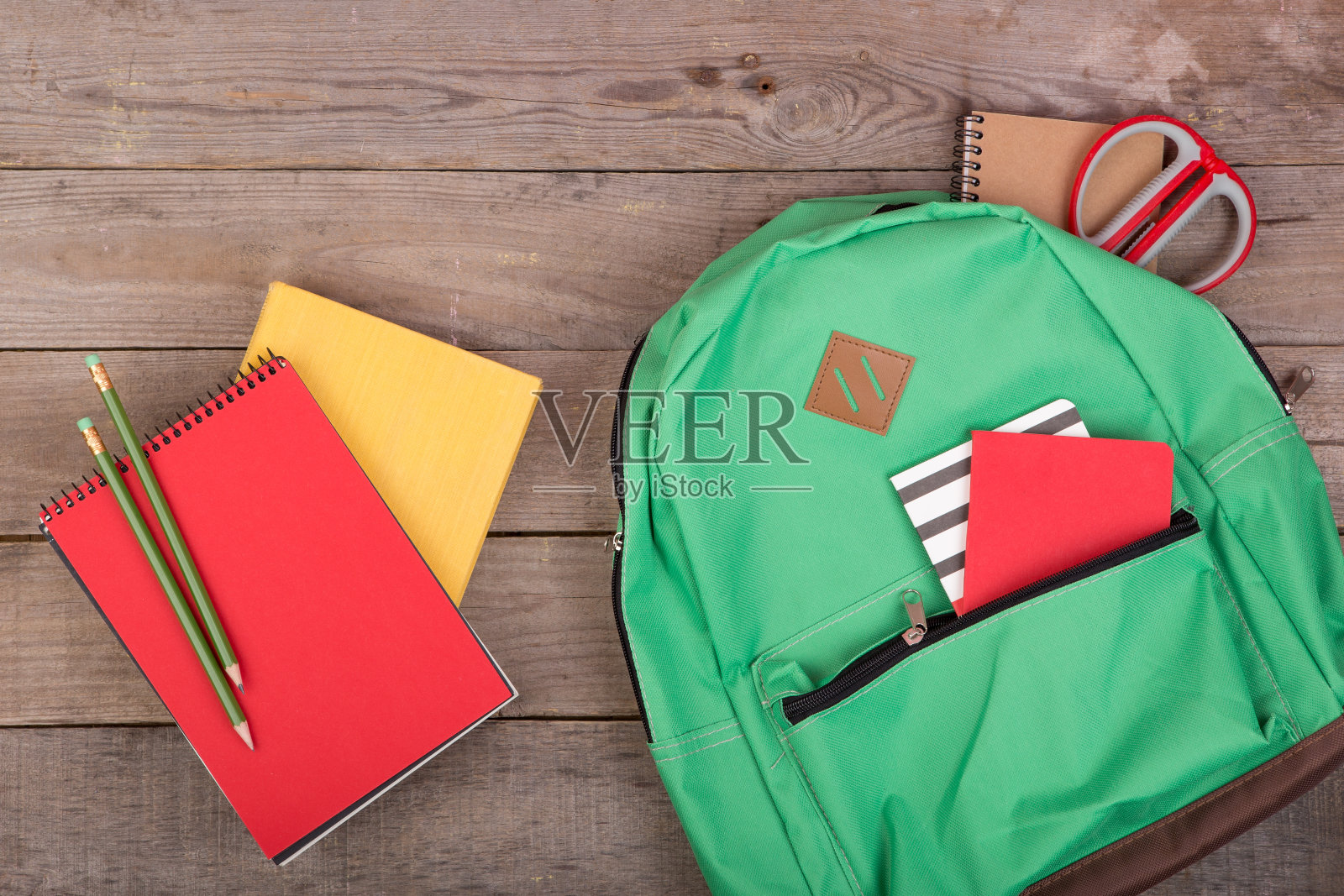书包和学习用品:书，铅笔，记事本，剪刀在棕色的木桌上照片摄影图片