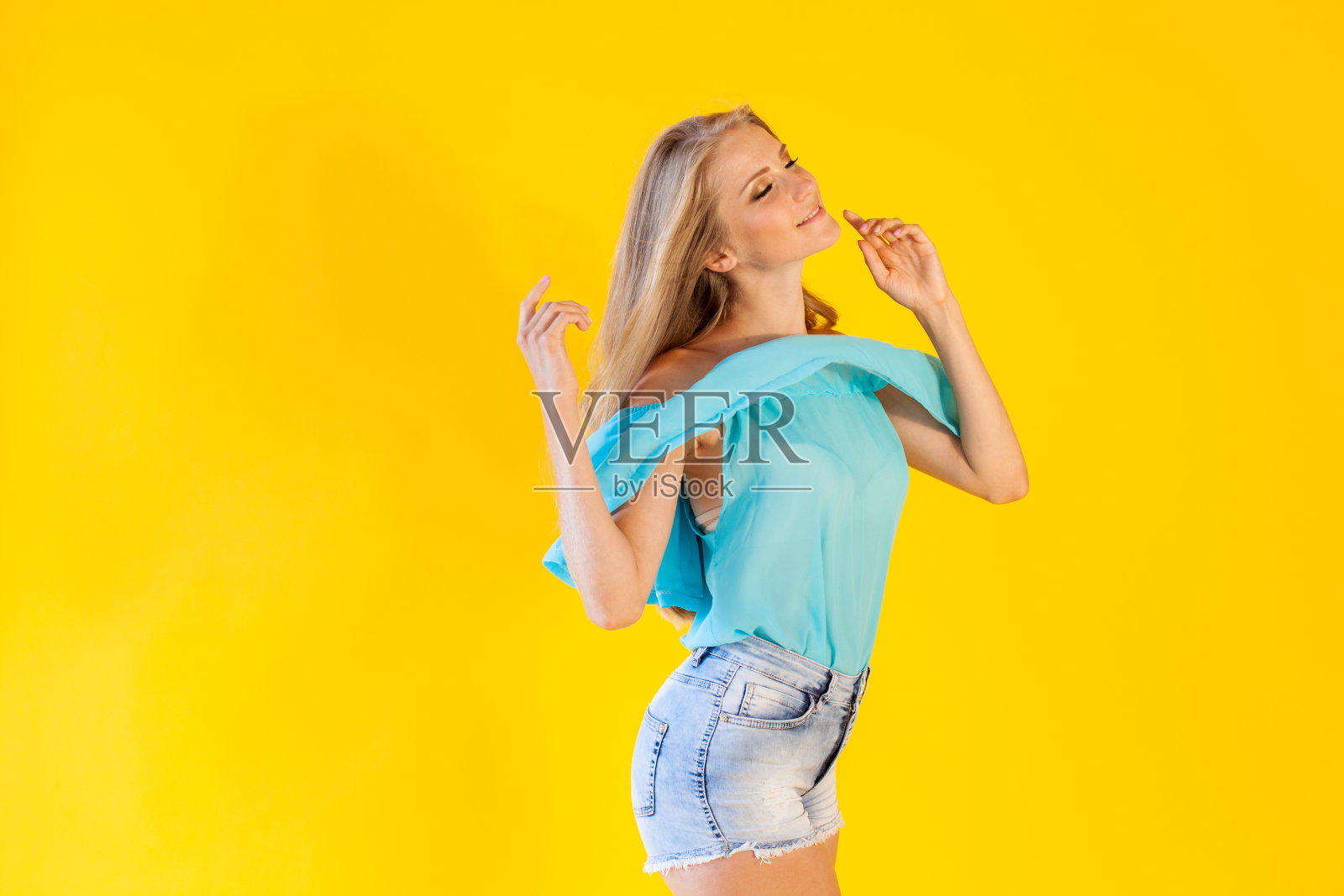 金发女孩穿着蓝色裙子，背景是黄色照片摄影图片