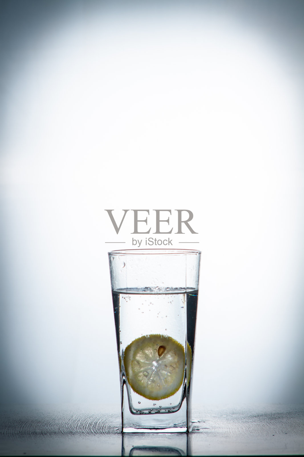 一片柠檬滴在一杯水里照片摄影图片