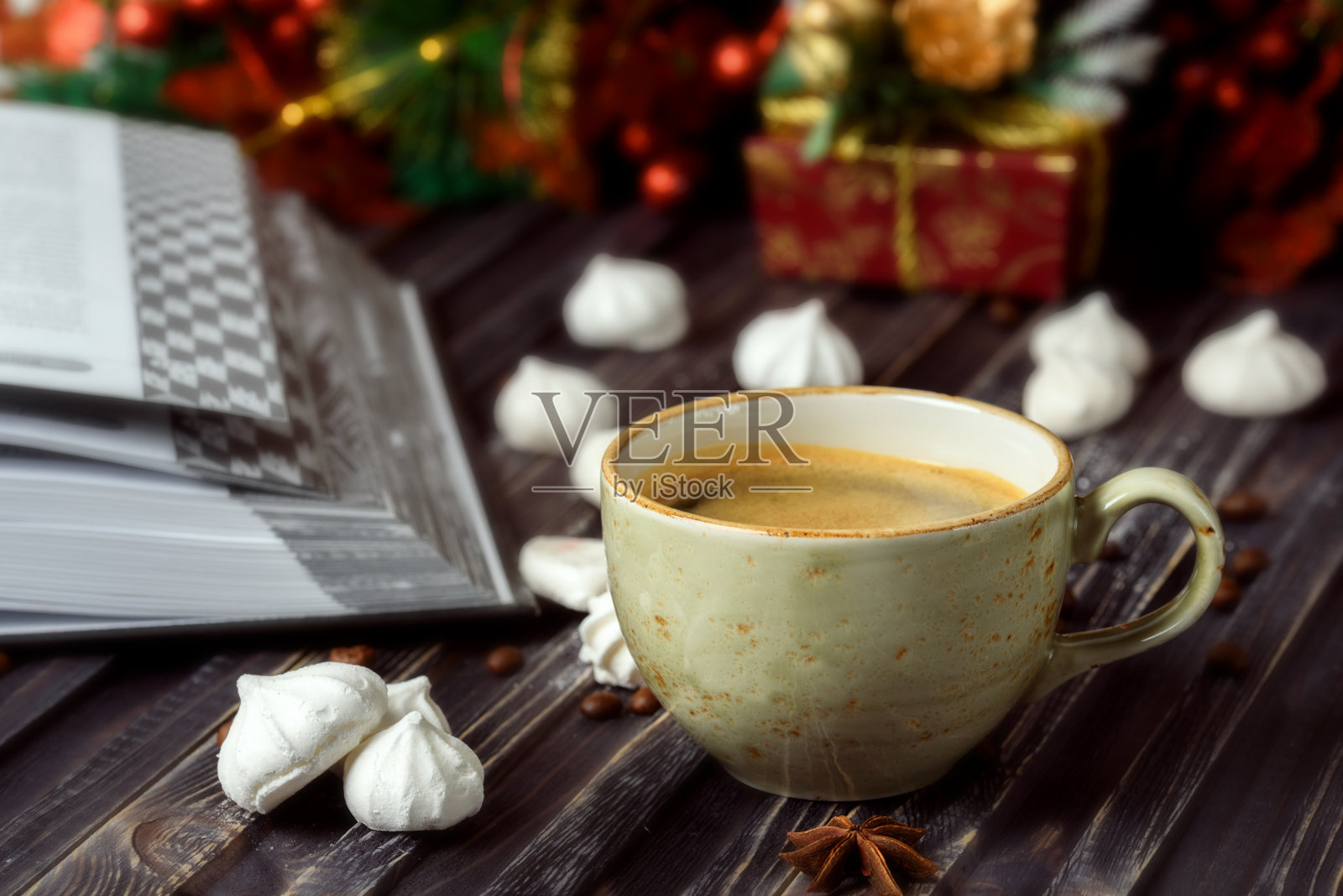 一杯配蛋白酥皮的咖啡，一本木制背景的书，新年的装饰照片摄影图片