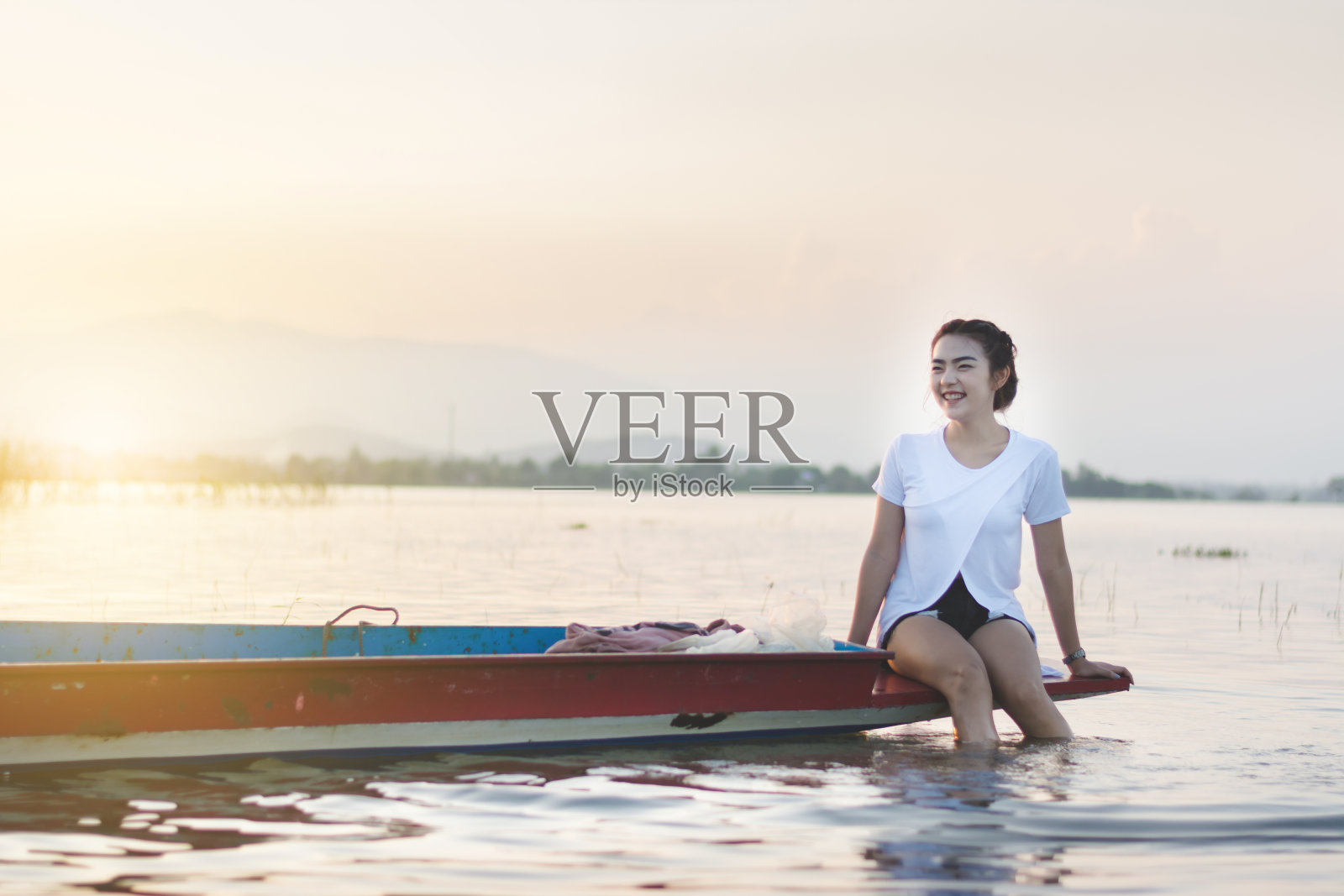 美丽的亚洲女子坐在渔船上，享受户外湖泊的自然风光照片摄影图片